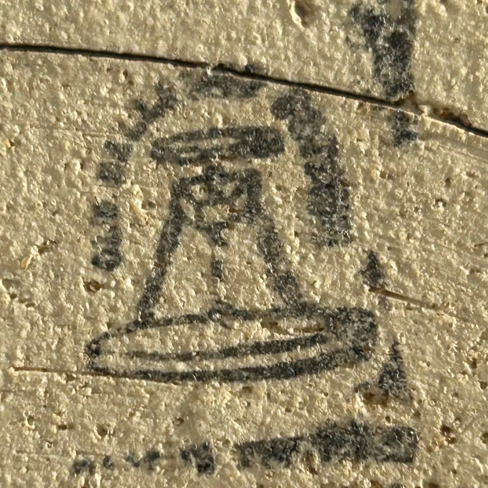 Close-up of stamped maker’s mark resembling a bell shape