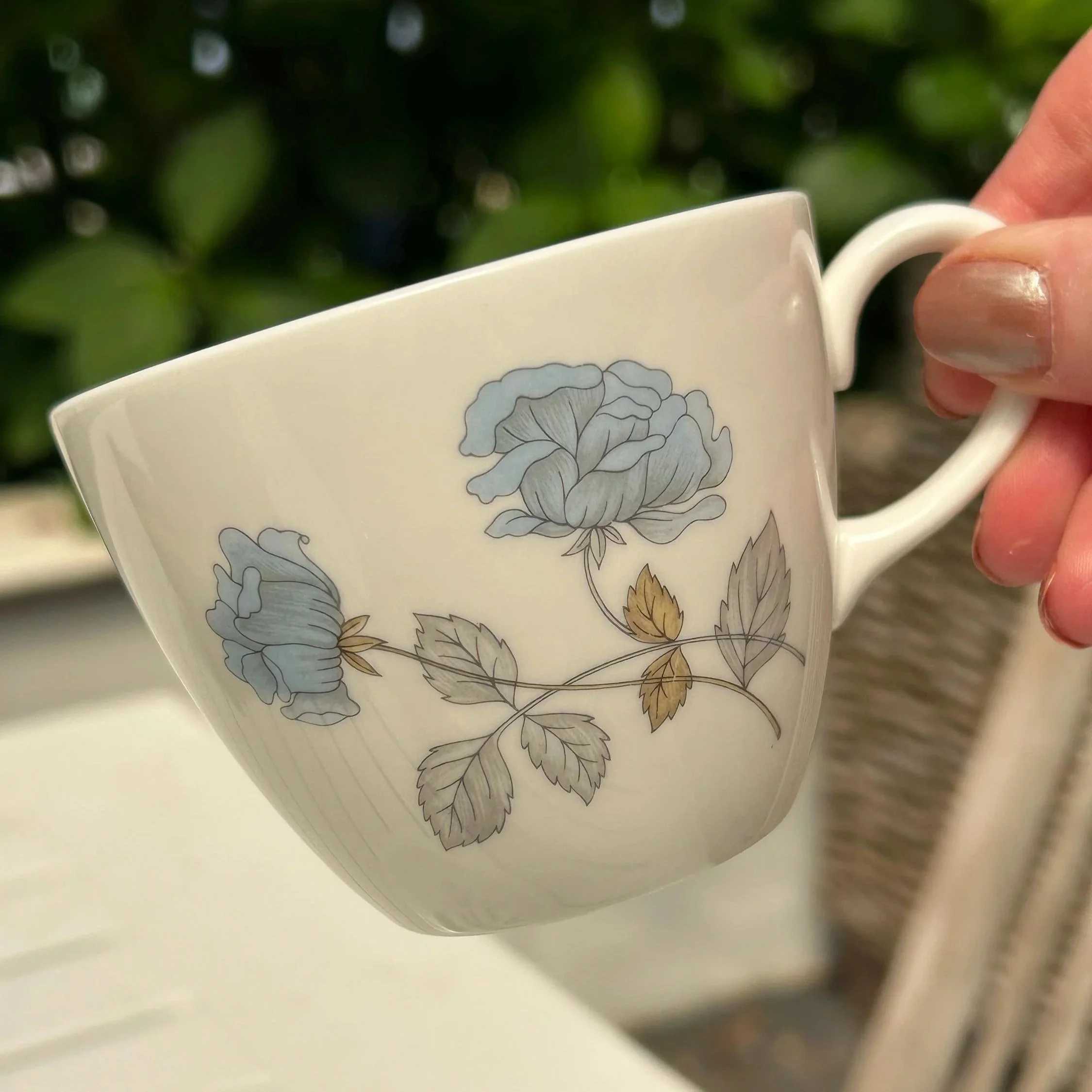 Side view of the Wedgwood teacup showing the pale blue rose motif and curved handle
