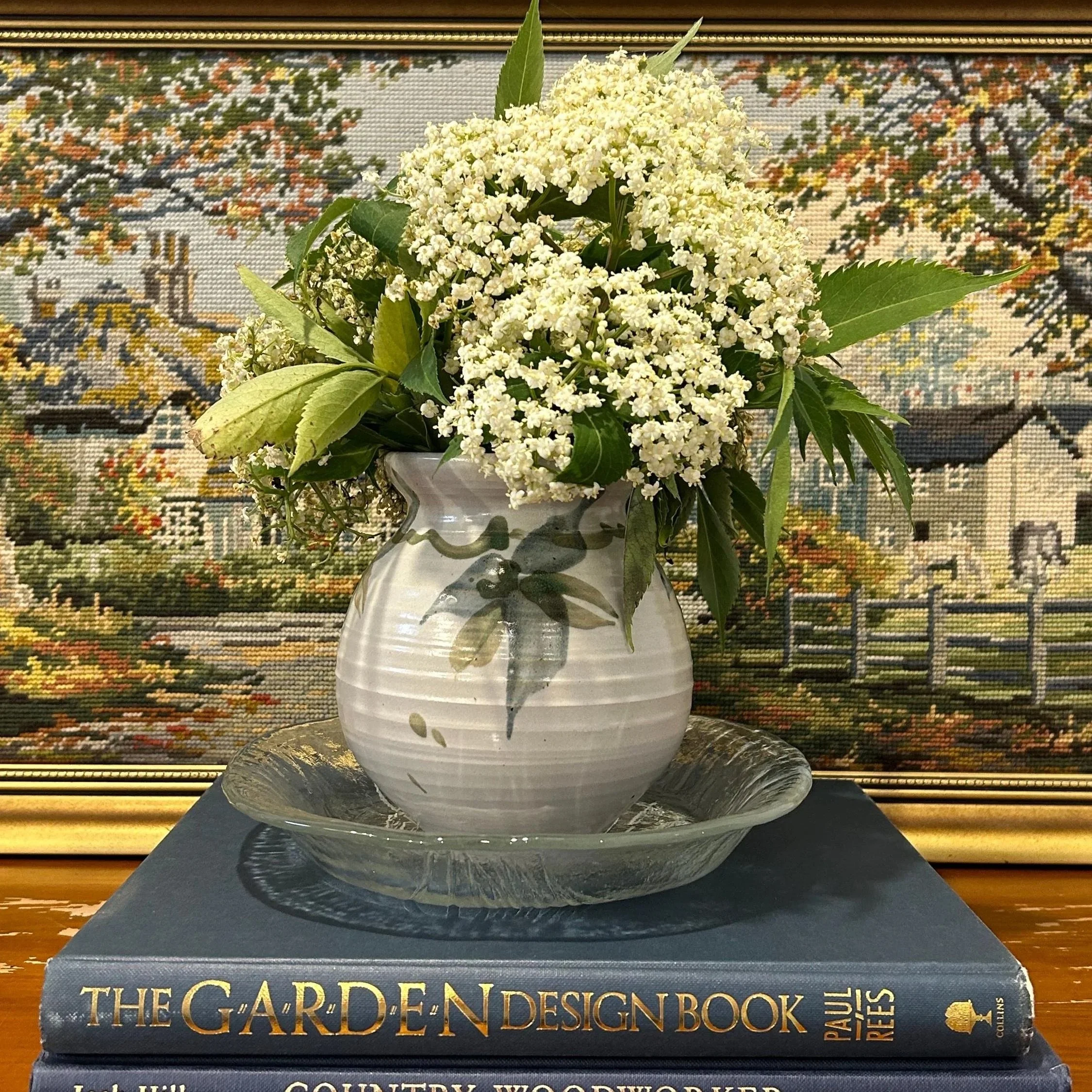 Laurelle Gordon pottery vase styled with fresh flowers on book stack with rustic painting background