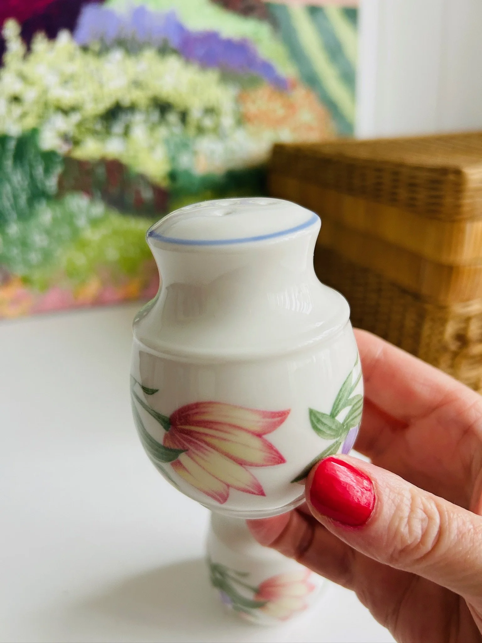 Single shaker held upright in hand at an angle, showing the side profile and floral pattern