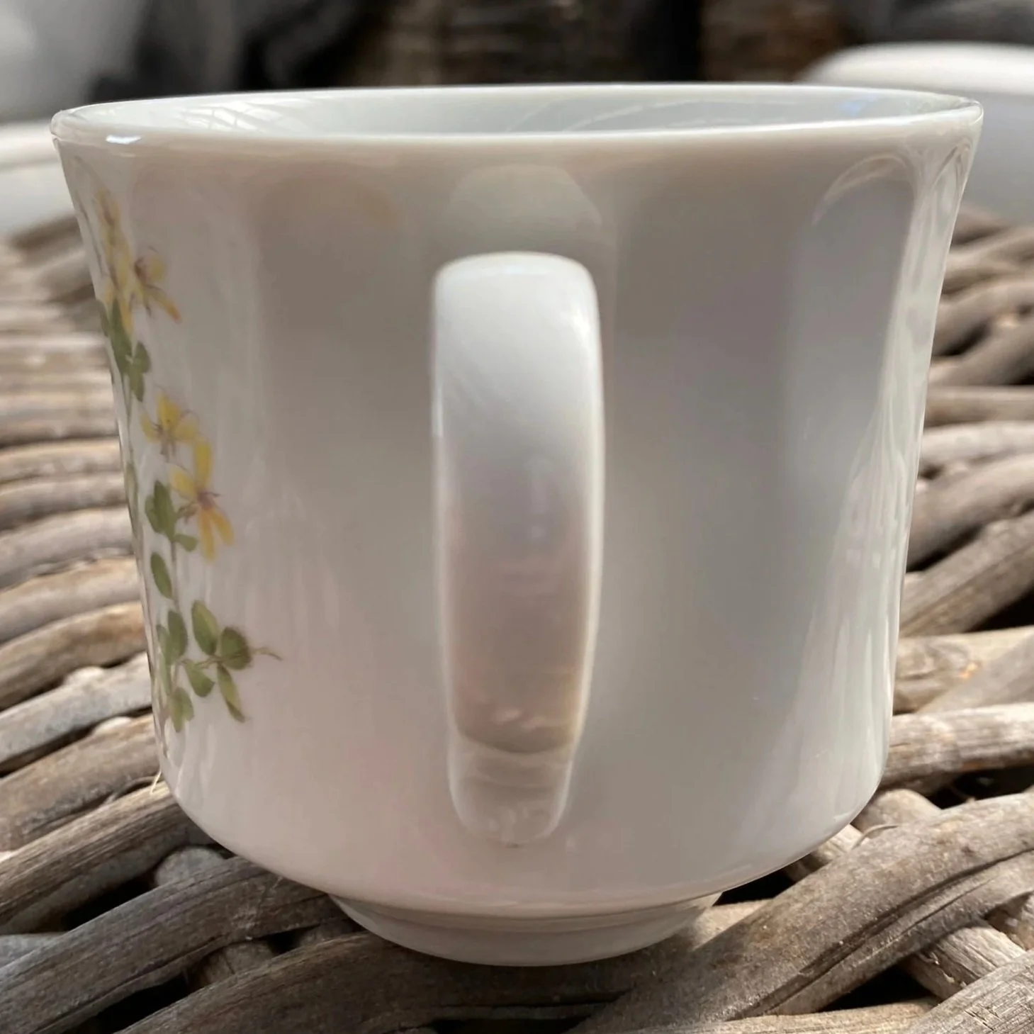 Rear view of ceramic cup showing handle and partial floral design