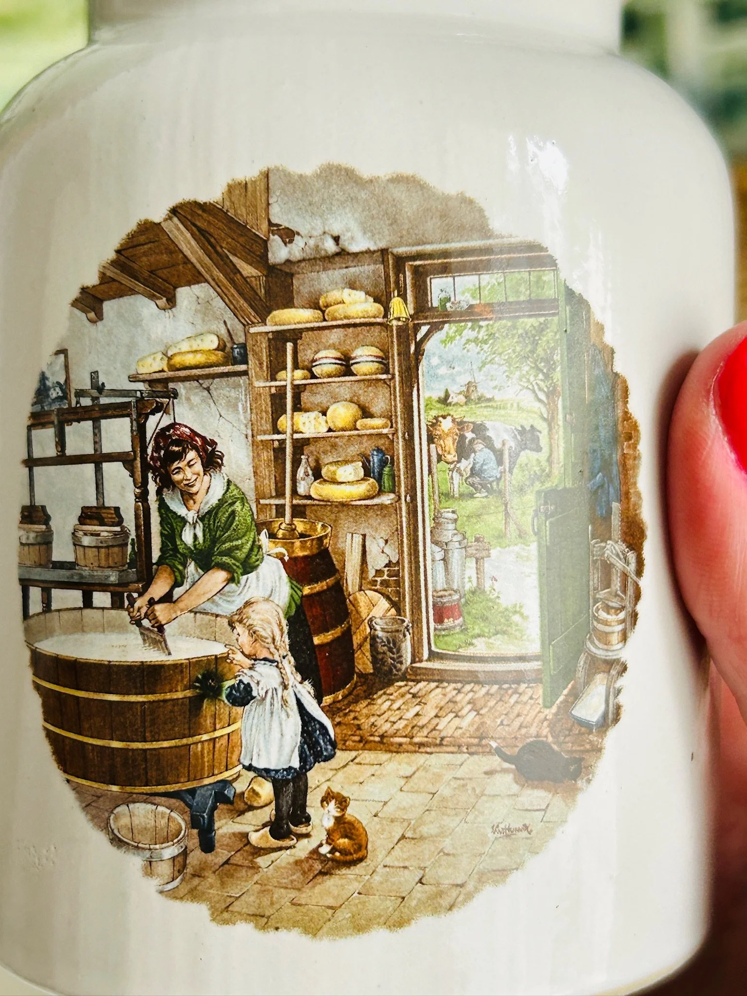 Detailed close-up of the cheese shop interior illustration, showing shelves, barrels, and figures in a cosy Dutch village setting.