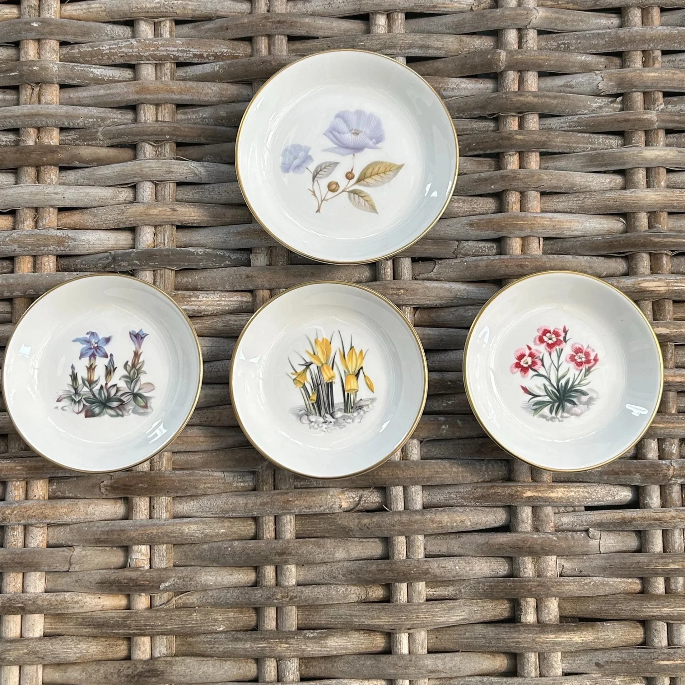 Overhead shot of all four Royal Worcester floral trinket dishes arranged on wicker
