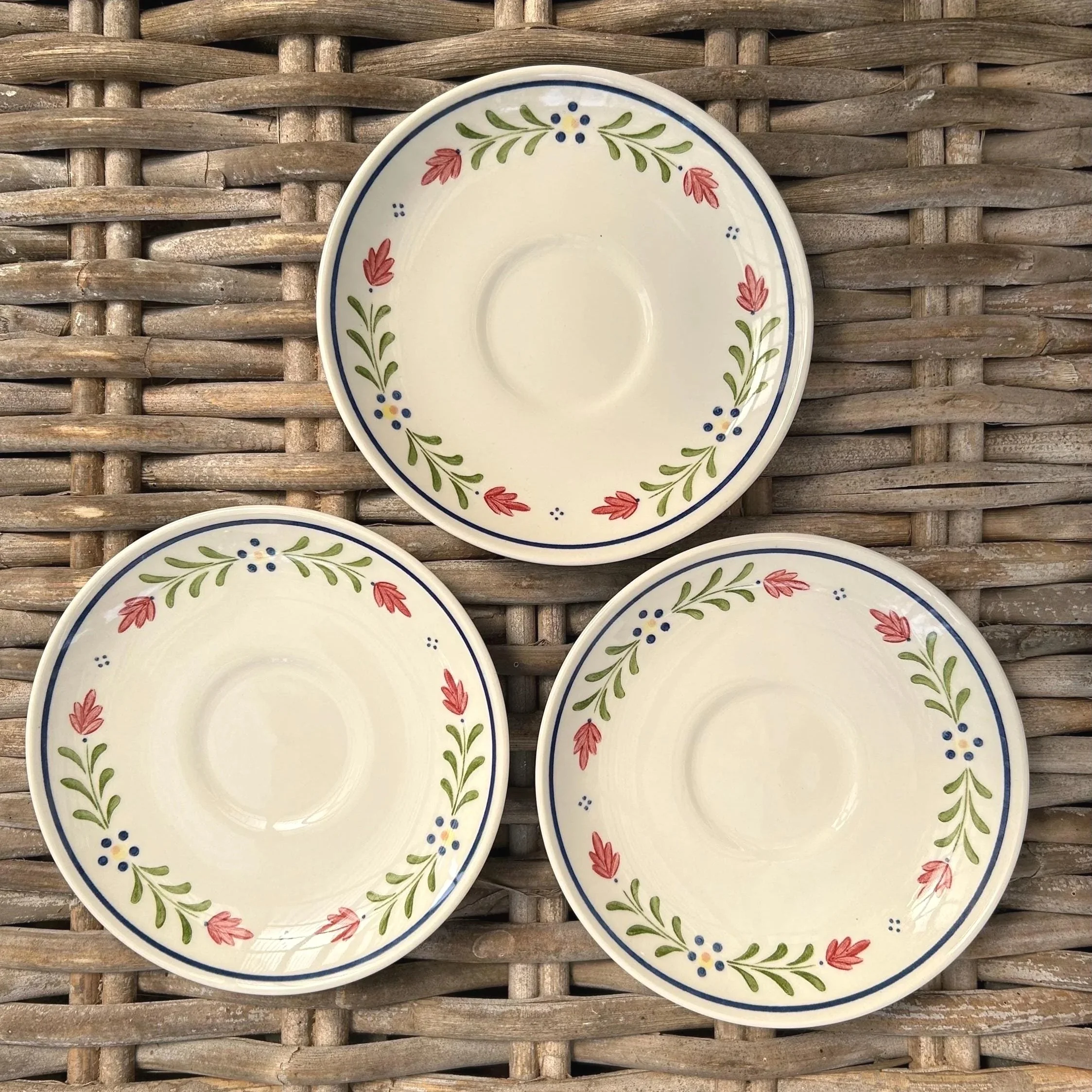 Three saucers and one side plate displayed flat showing matching floral rim
