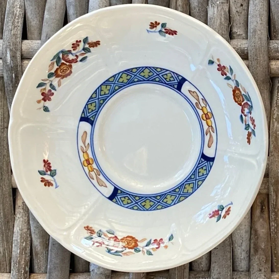 Close-up of single saucer showcasing detailed blue border and floral design