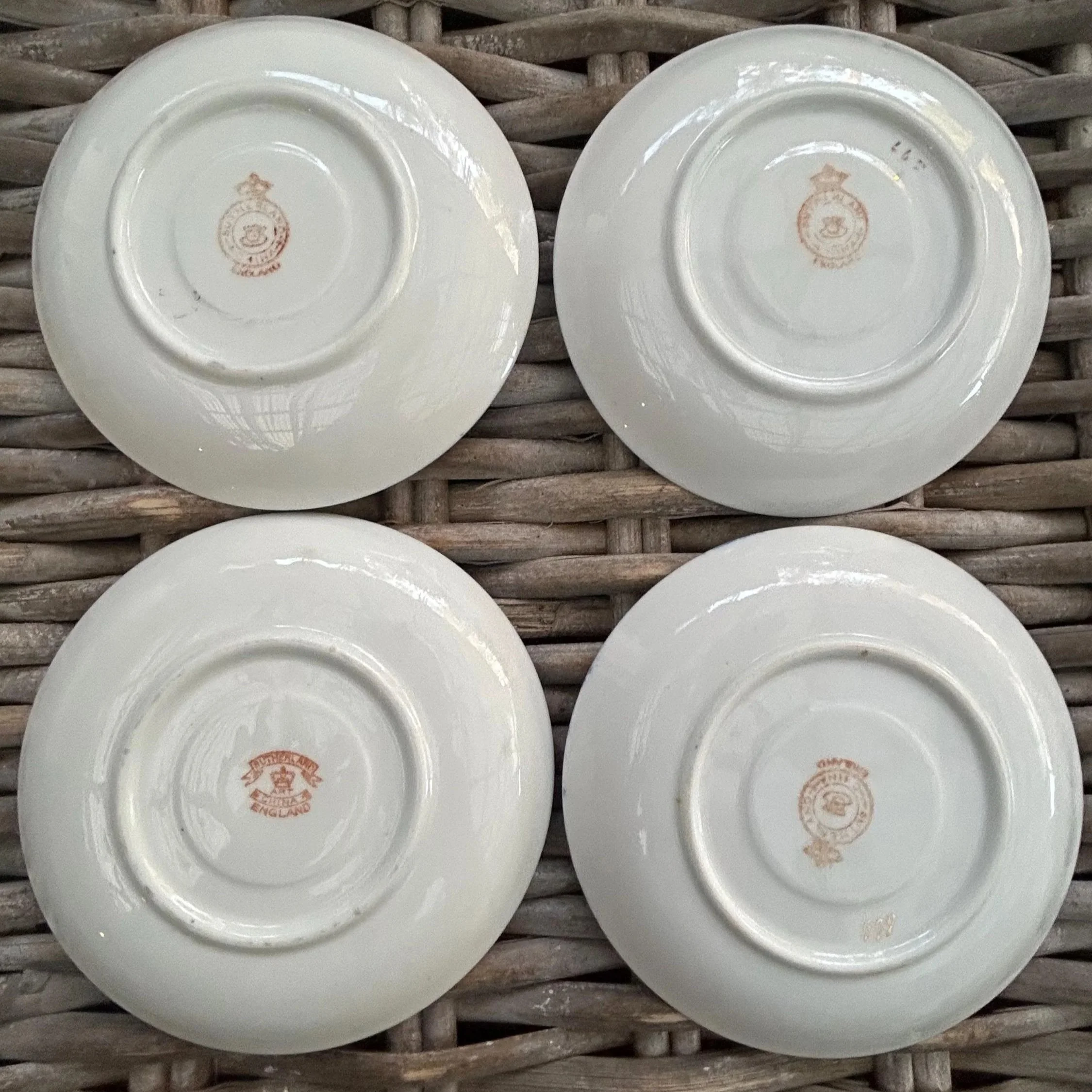 Four saucers with visible backstamps, showing variation in design