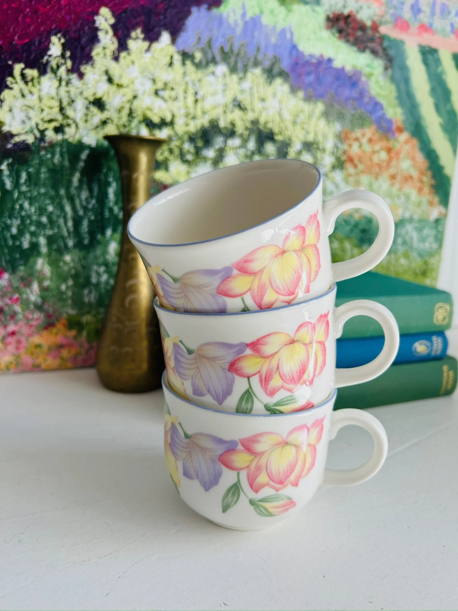 Stack of three Royal Doulton Blooms teacups, showing the repeated floral motif, handles, and blue-edged rims