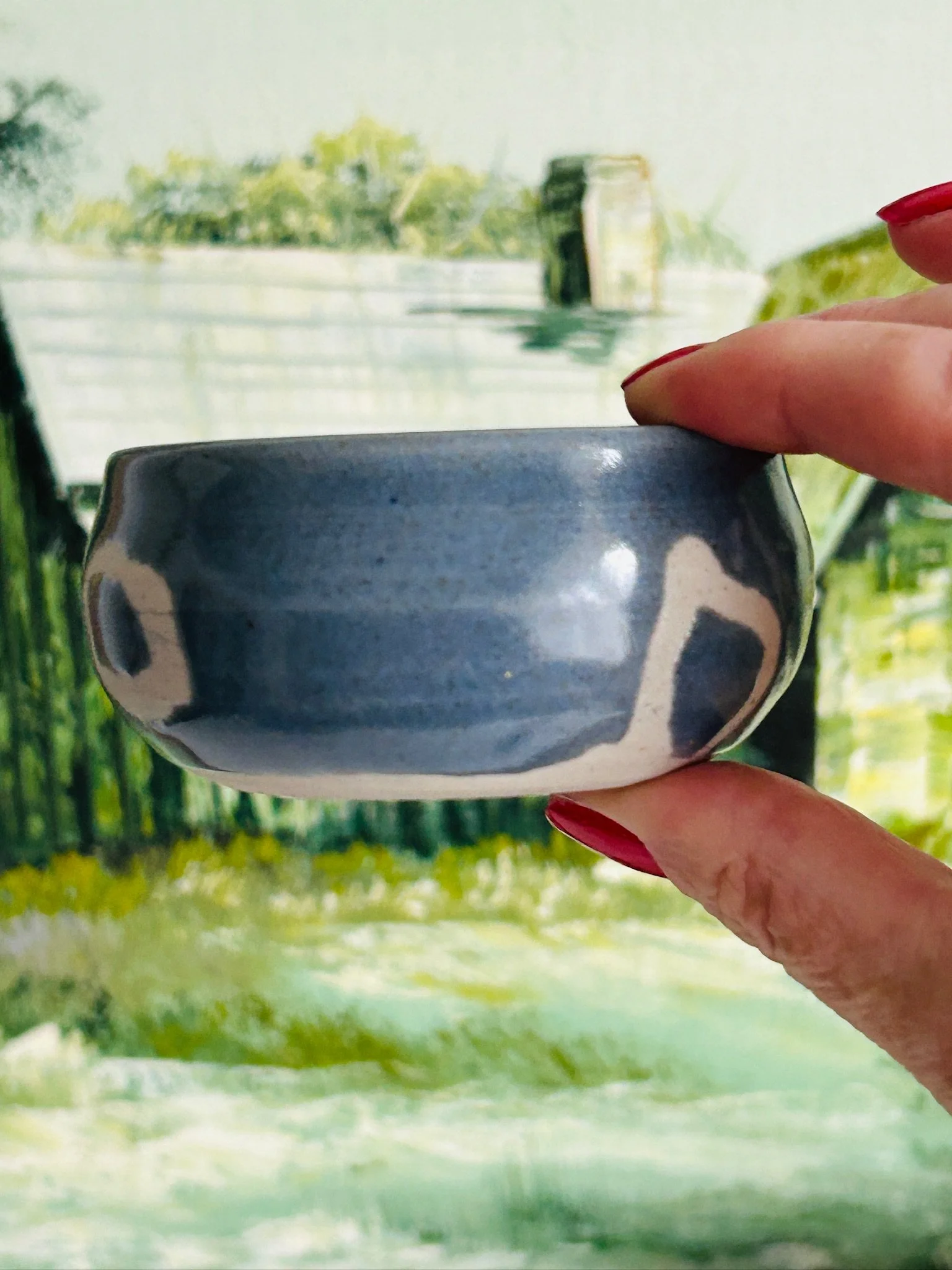 Side profile of the handmade ceramic bowl held in hand, showing the rounded form and ring motif detail