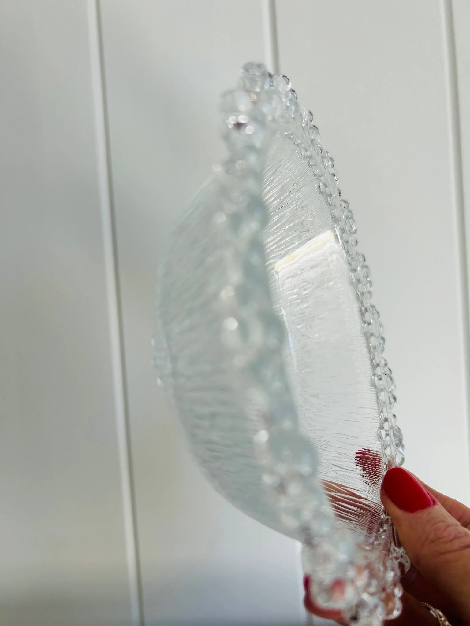 Side profile of the bowl held upright, highlighting its shallow curved shape and beaded rim detail.