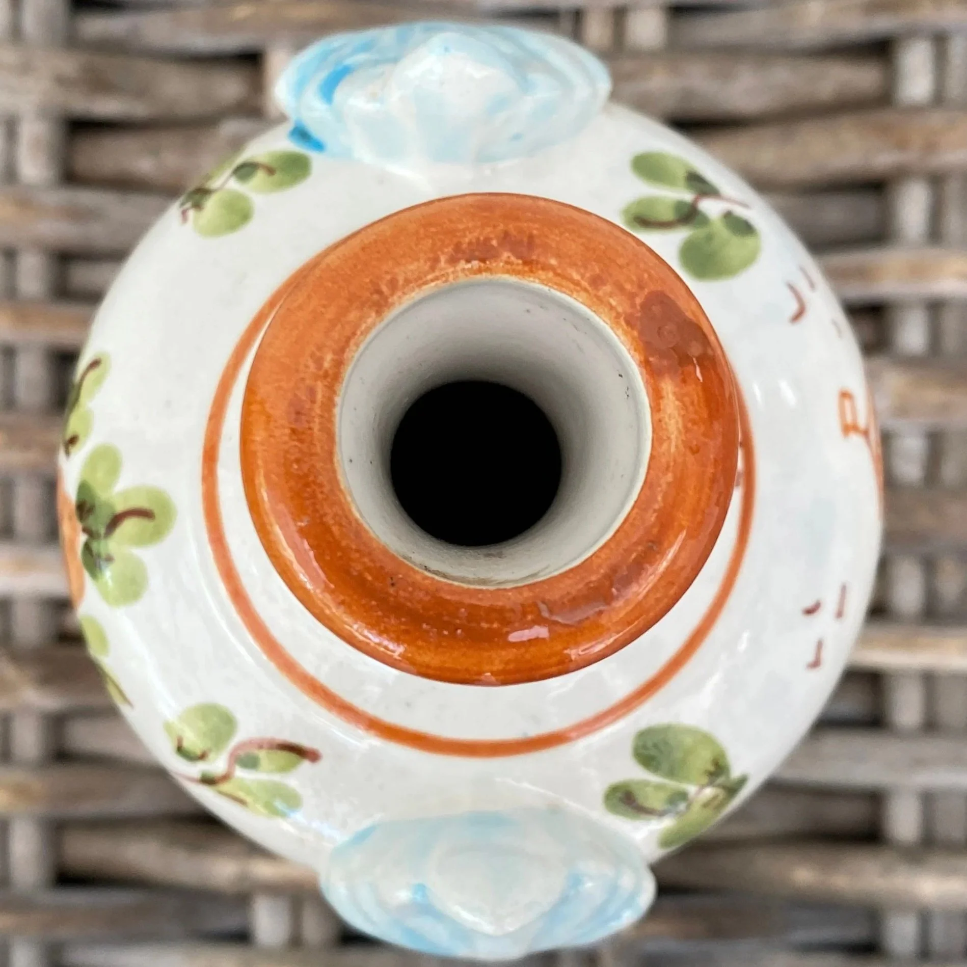 Overhead view of vase opening with orange terracotta rim and floral accents