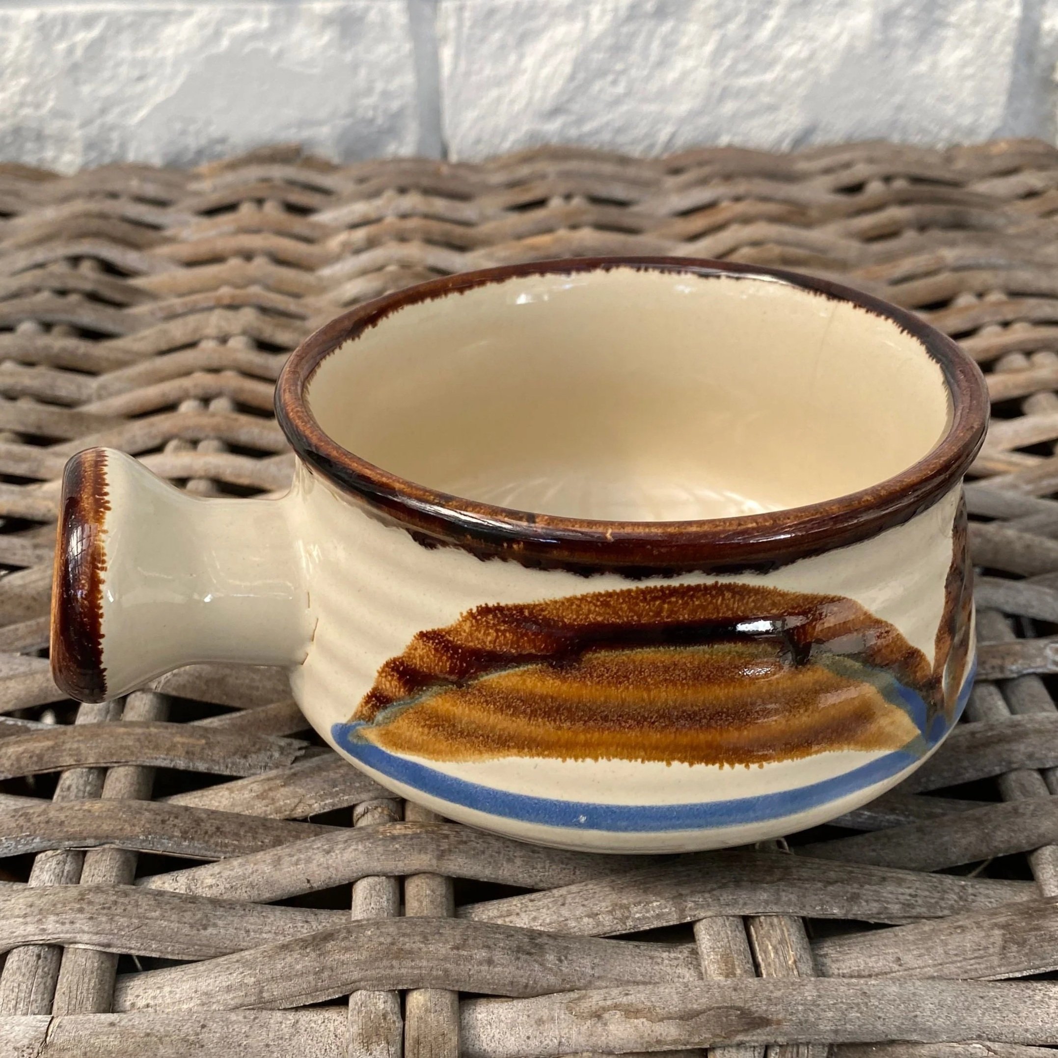 Side view of vintage JI Stonecrest stoneware soup bowl with handle in Tramore pattern, showing brown and blue design on cream glaze