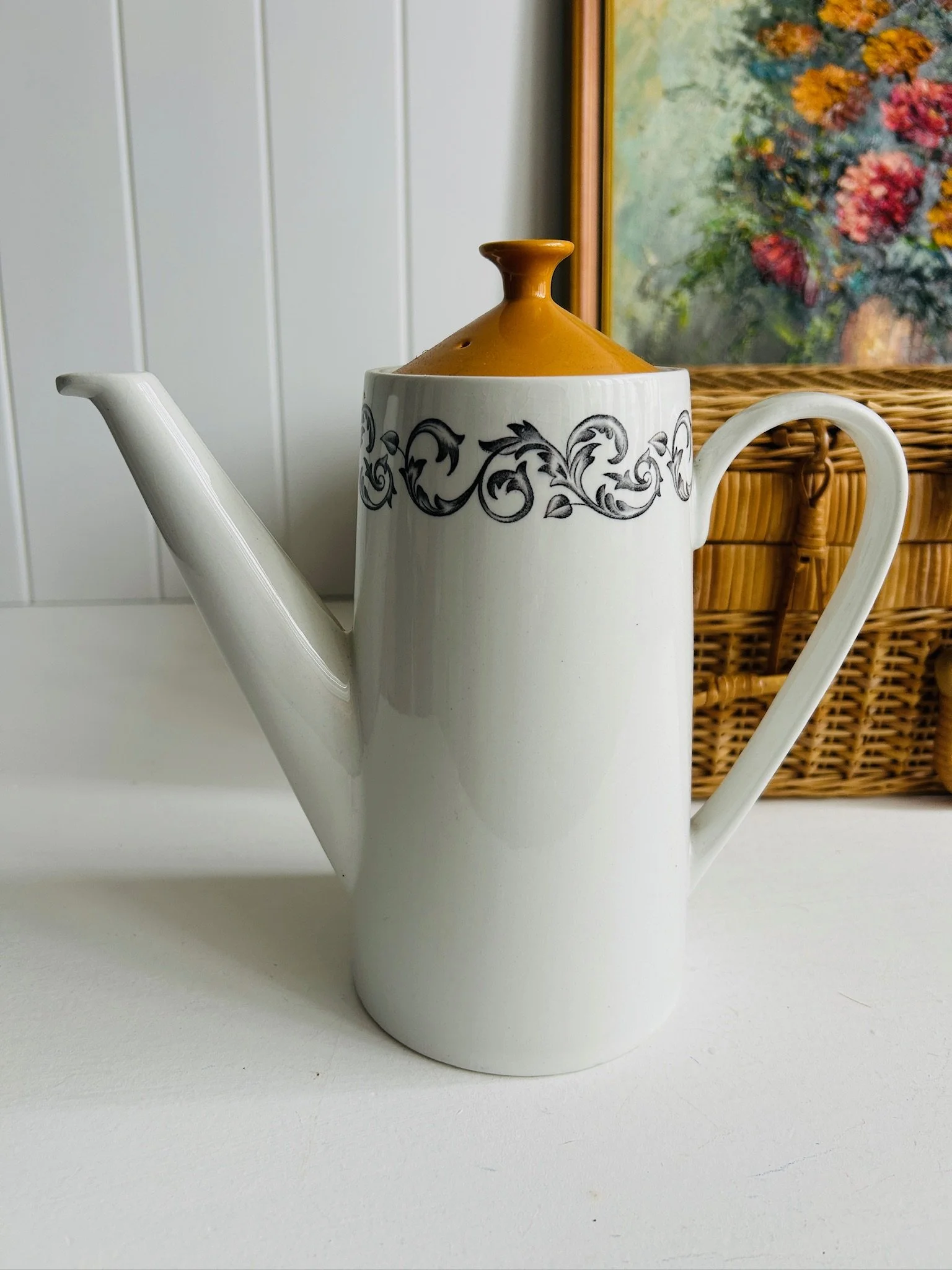 Front view of vintage Johnson Brothers coffee pot in the DJ 100 pattern, white earthenware with black scrollwork band and bright orange lid.