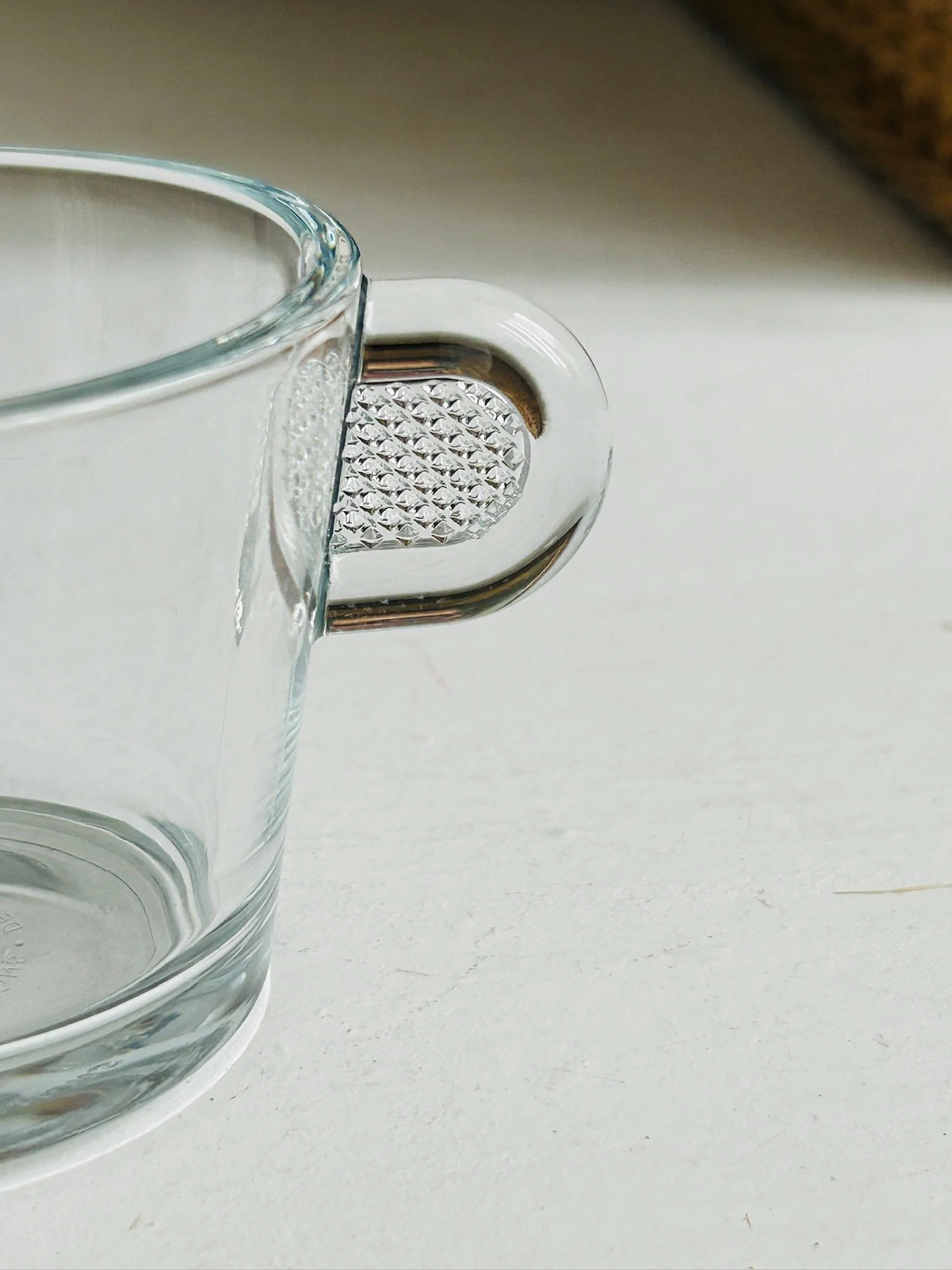 Side close-up of a Nespresso cup handle showing the textured insert detail in the clear glass