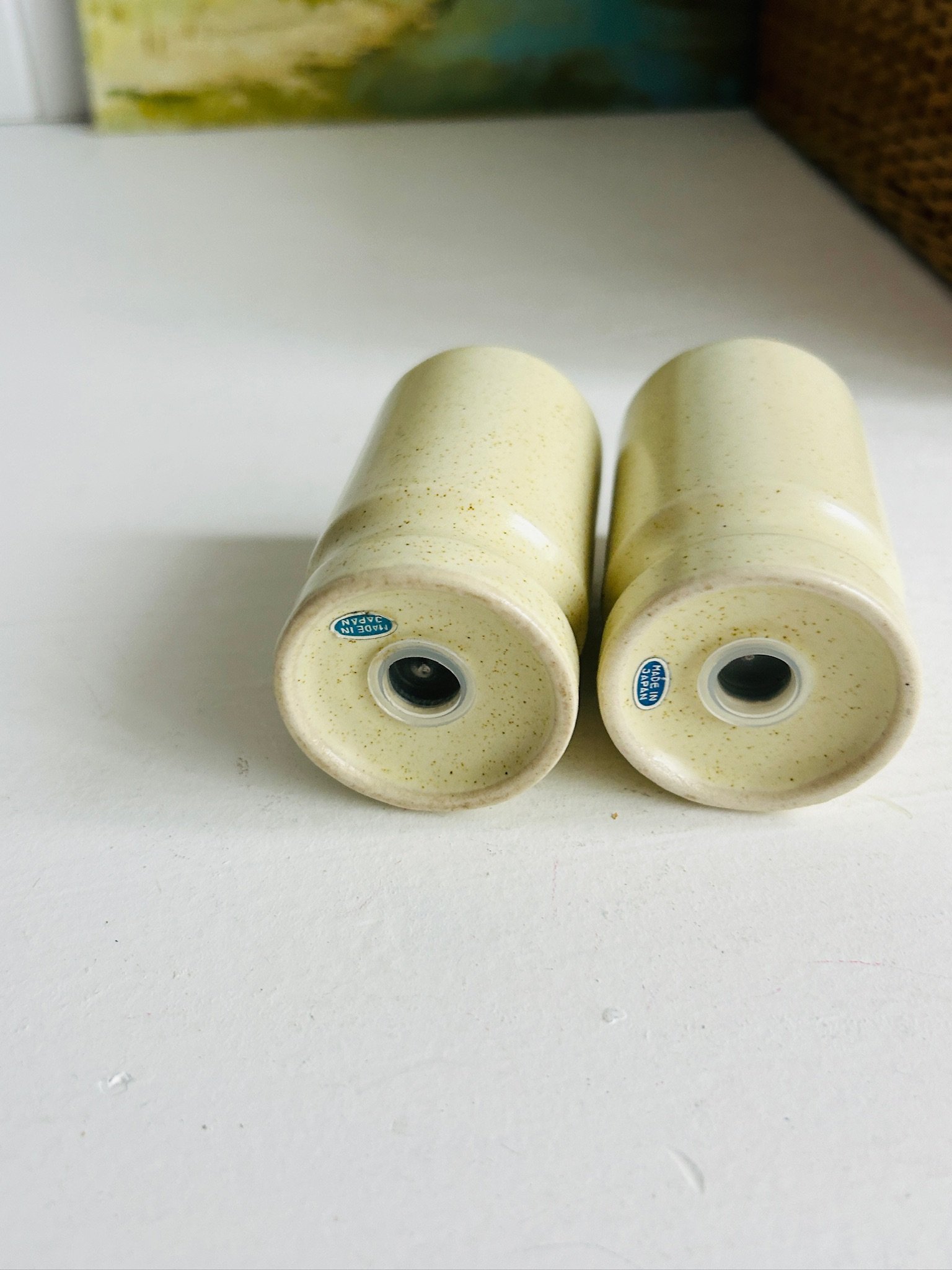 Underside view of both shakers laid on their sides, showing the base openings and small blue “Made in Japan” labels
