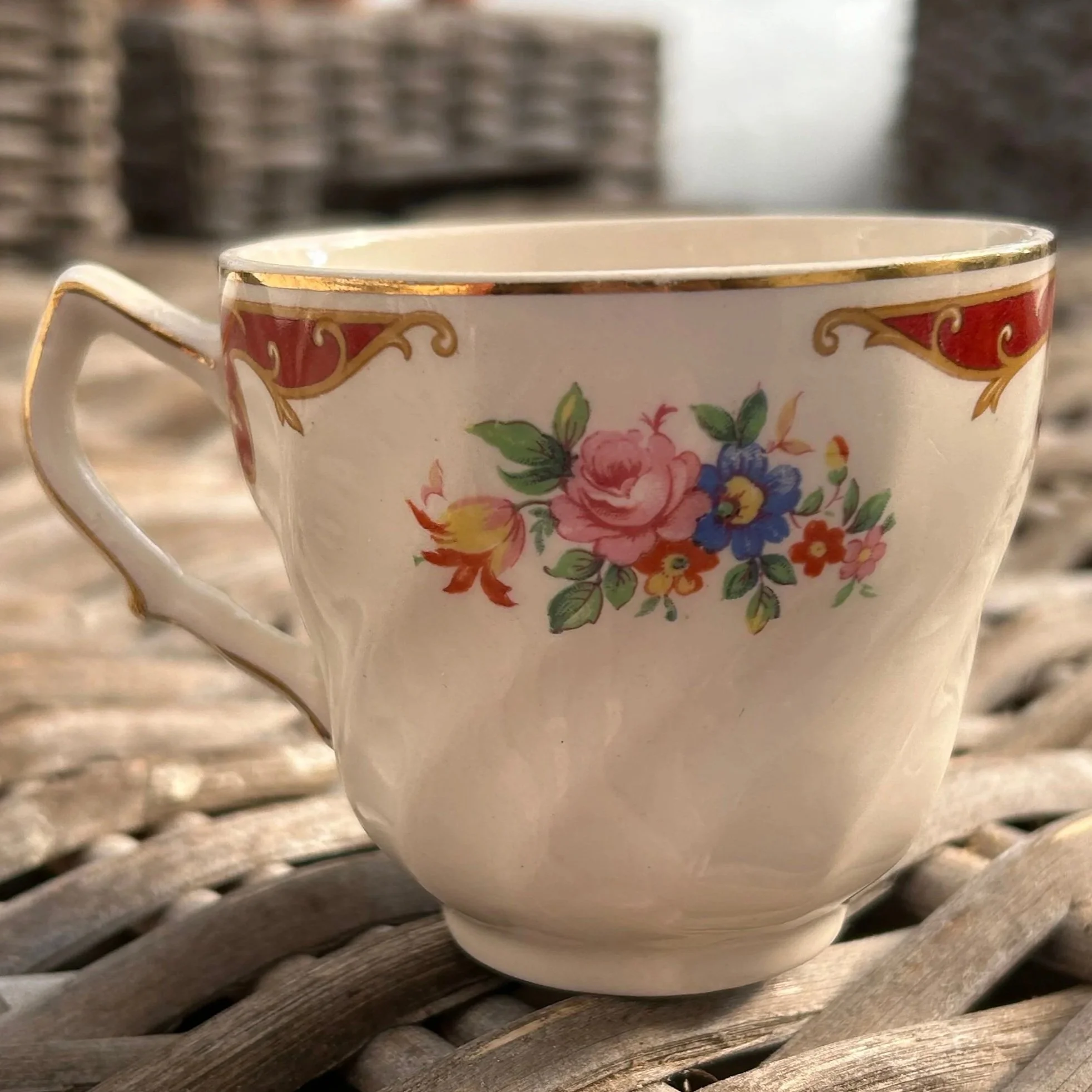 Close-up of one teacup showing floral transfer and crimson scroll design
