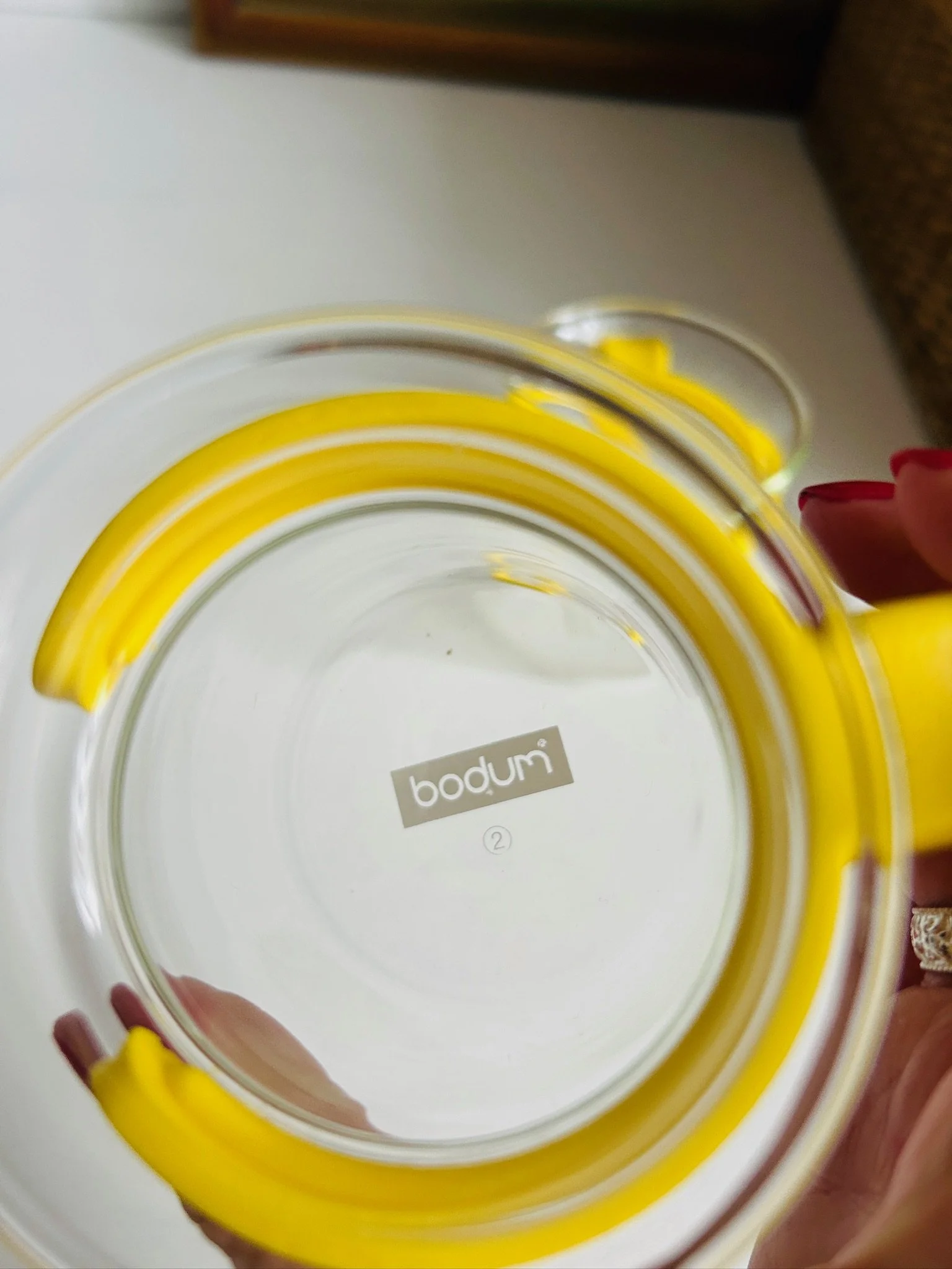 Top-down view of the base of a Bodum Picard glass cup showing the moulded Bodum logo and blue plastic holder.