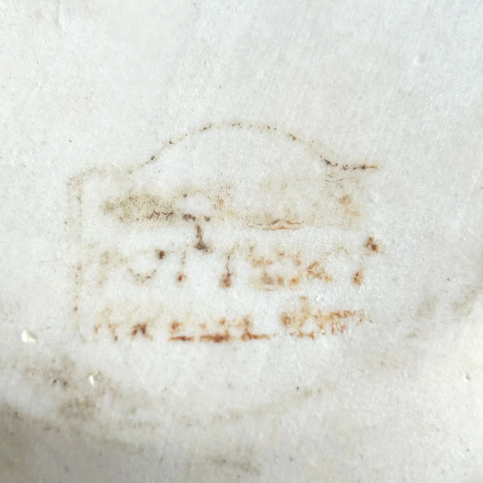 Close-up of faded maker’s stamp on base