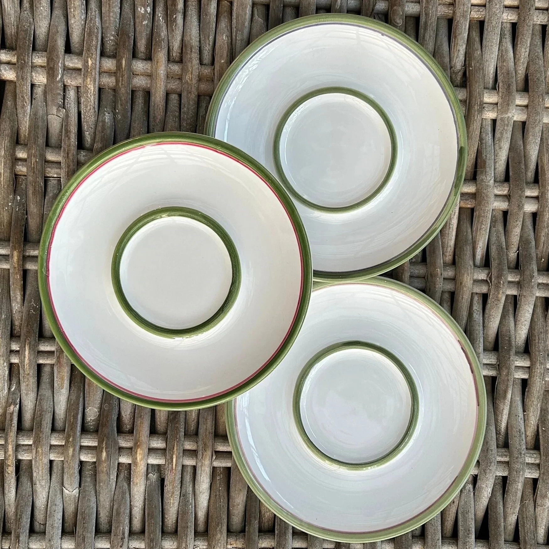 Overhead view of the three matching Italian ceramic plates arranged on wicker