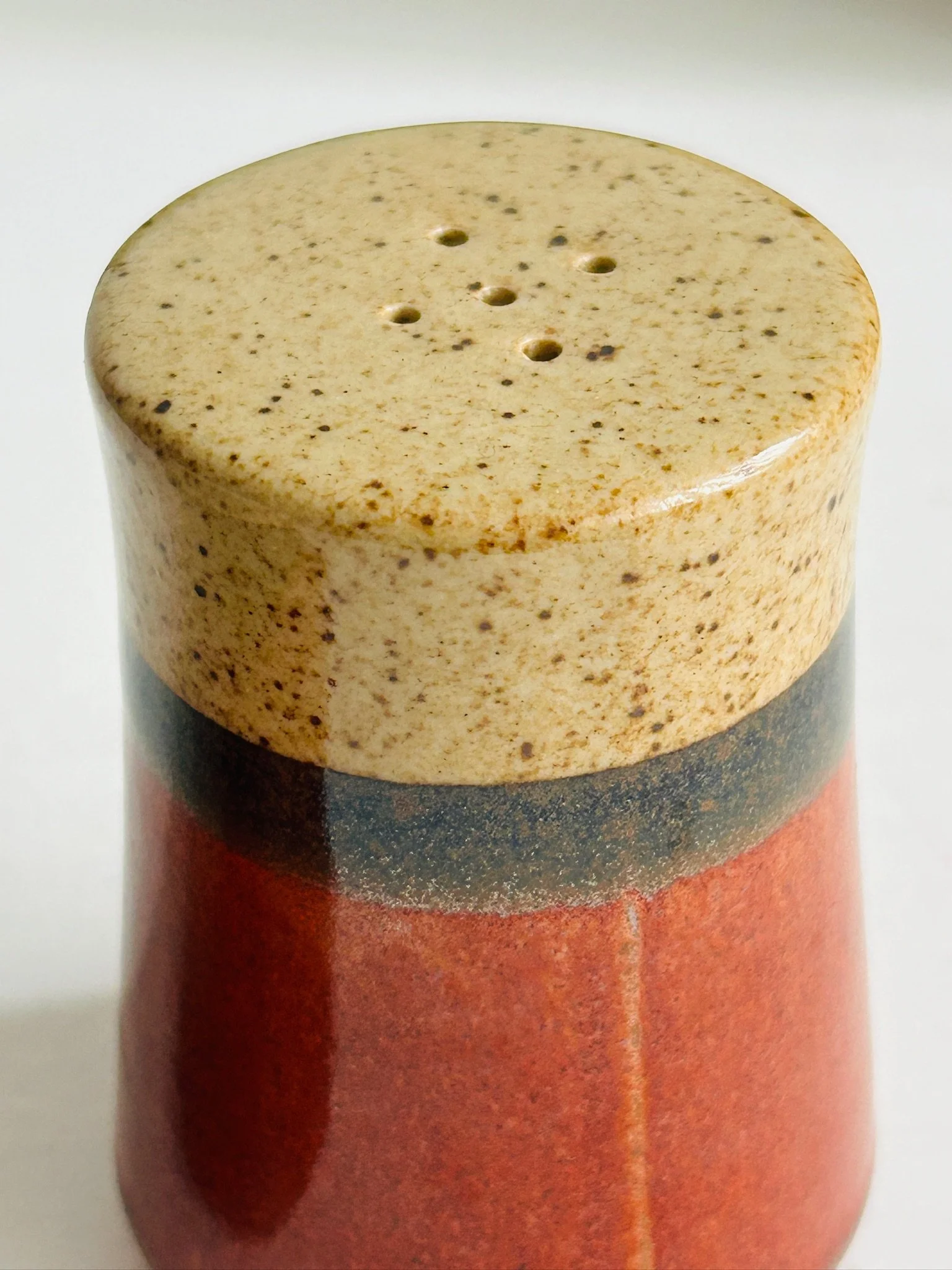 Close-up of the top and upper body of one shaker, showing the speckled cream glaze and dark brown band.