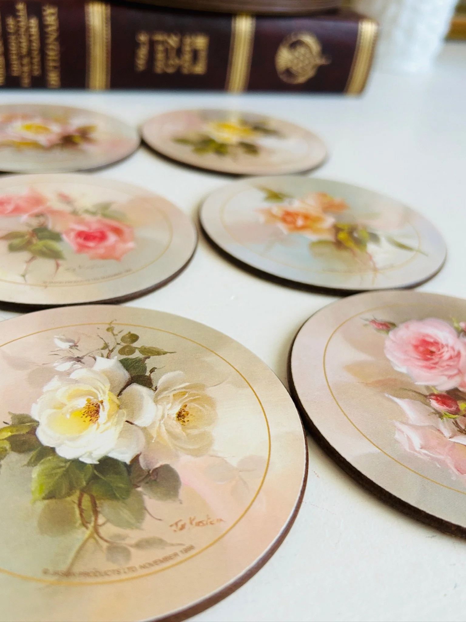 Four round Jason rose placemats spread out showing pink, white and blush rose designs by Jill Kirstein