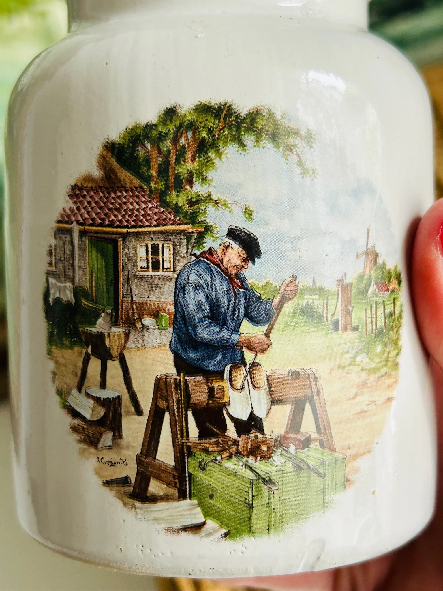 Close-up of the outdoor cobbler scene on the second pot, showing a seated shoemaker beside a cottage and trees.