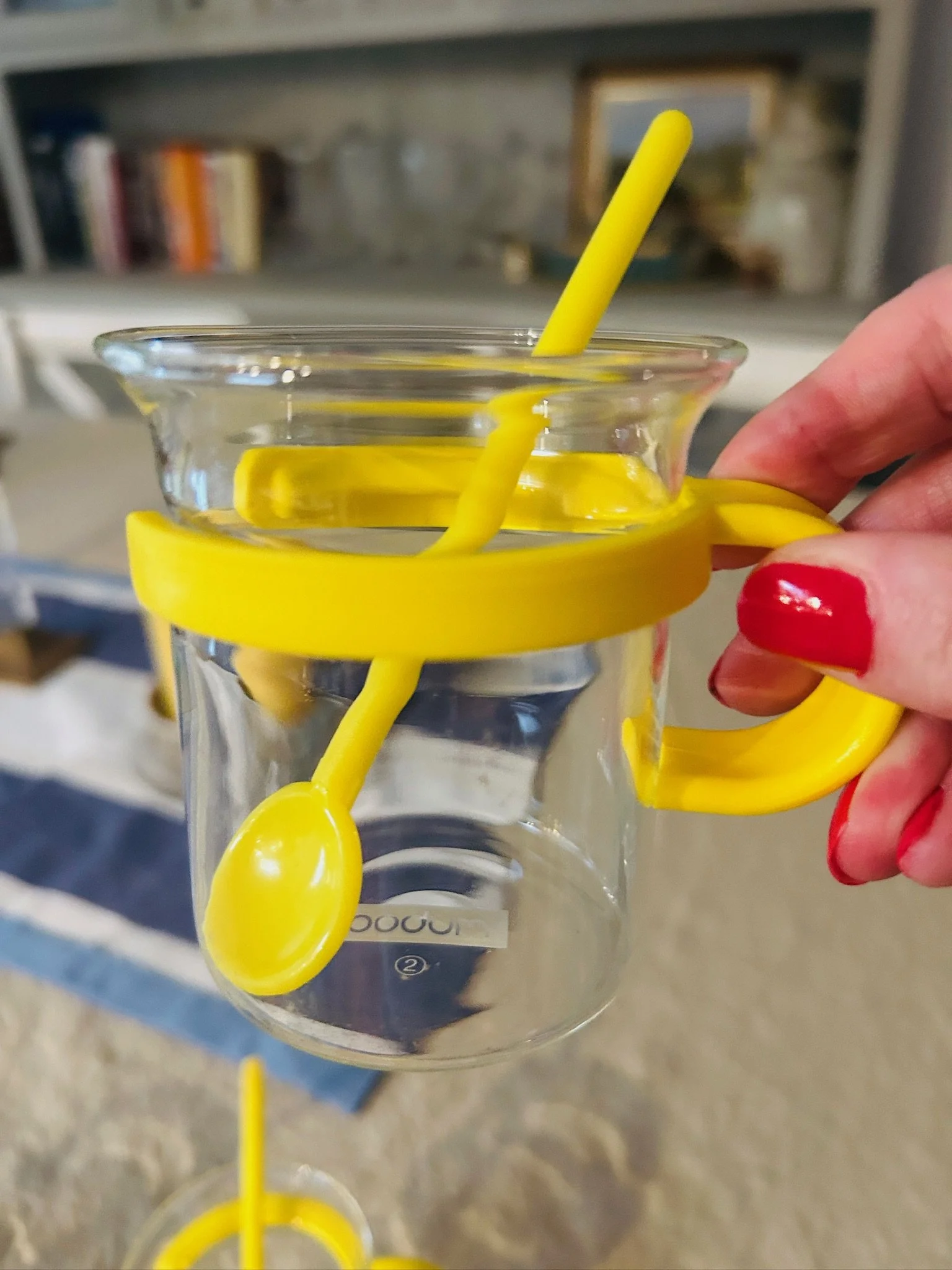 Close-up of a single Bodum Picard cup with yellow holder and spoon, shown in hand to highlight the handle and size.
