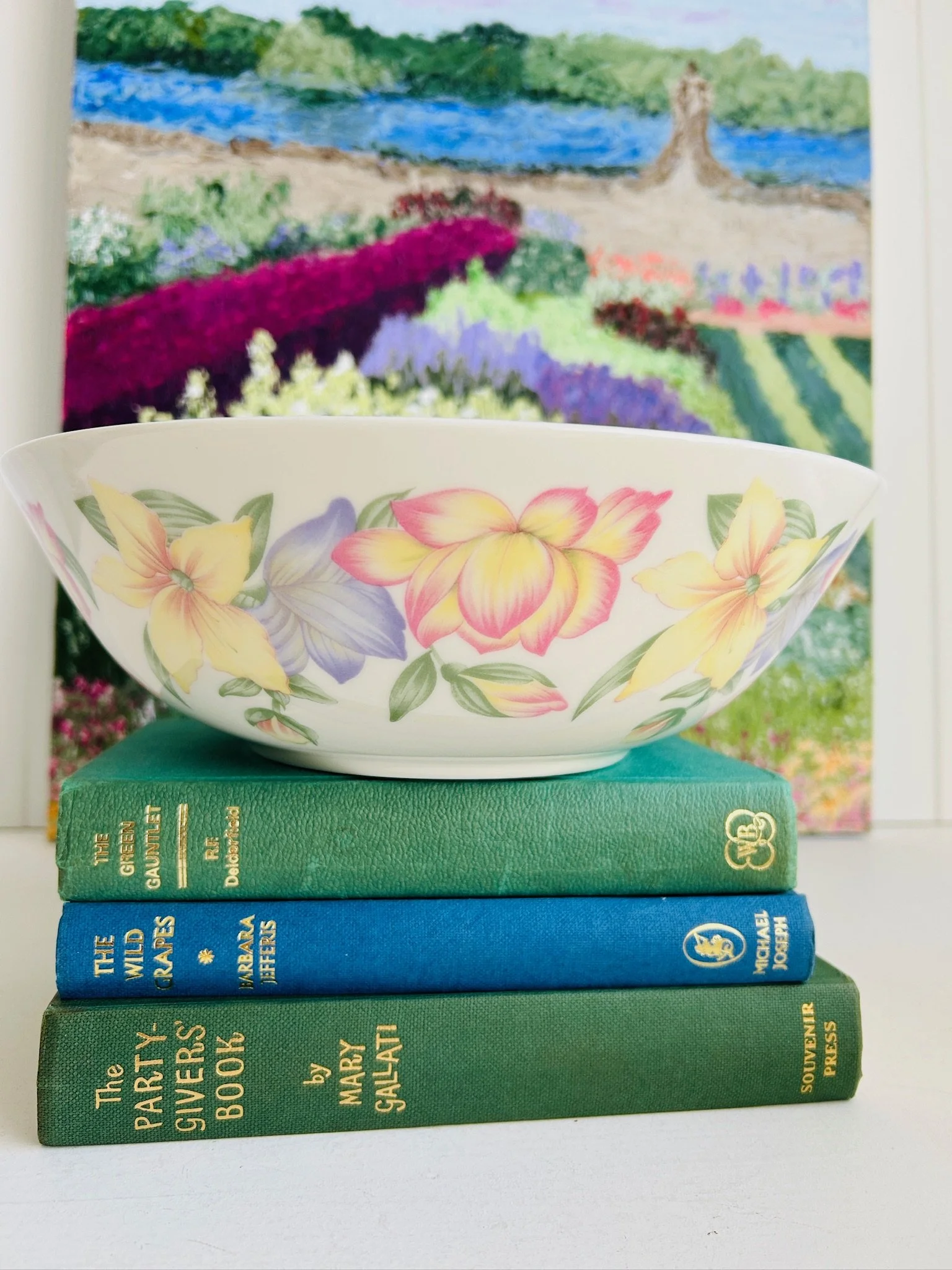 Royal Doulton Blooms large serving bowl displayed on stacked books, showing the pastel floral exterior design in yellow, pink, and purple