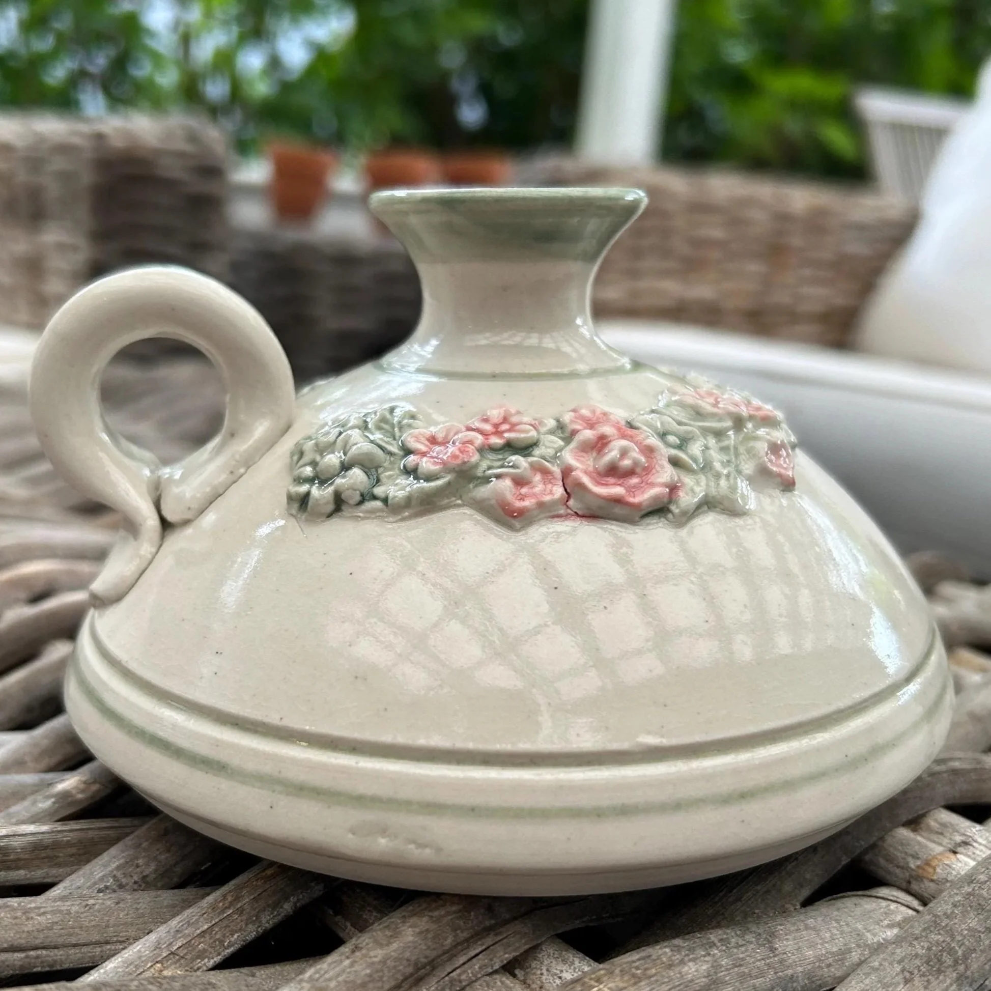 Side view of floral pottery candlestick holder showing pink and green flower band