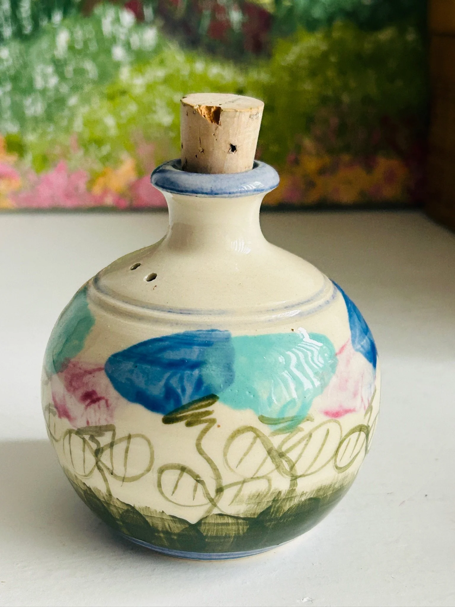 Front view of single New Moon Pottery shaker showing blue and aqua floral motif with looping green vine detail