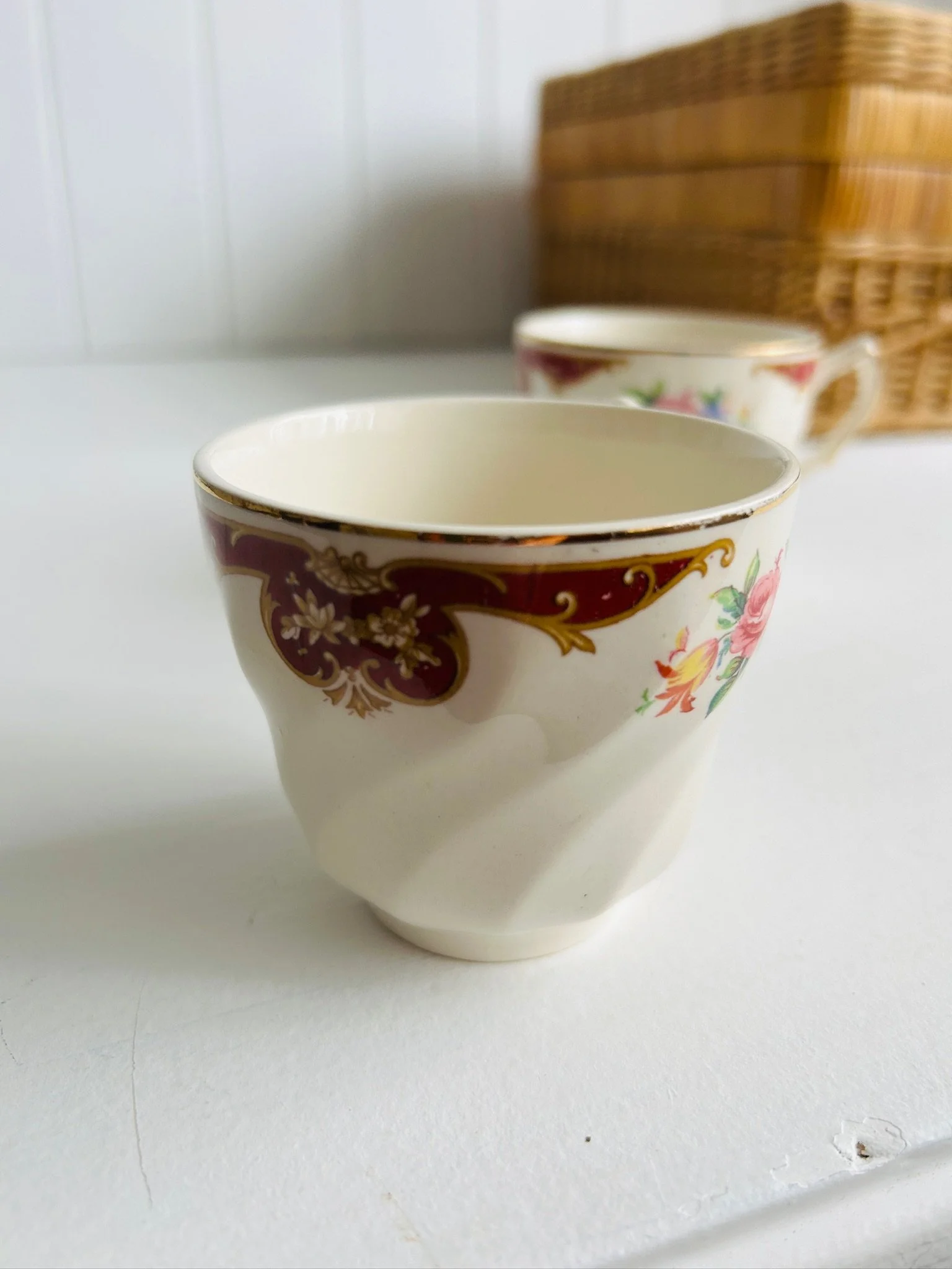 Side profile of a single teacup showing the burgundy and gold border detail and gently twisted shape