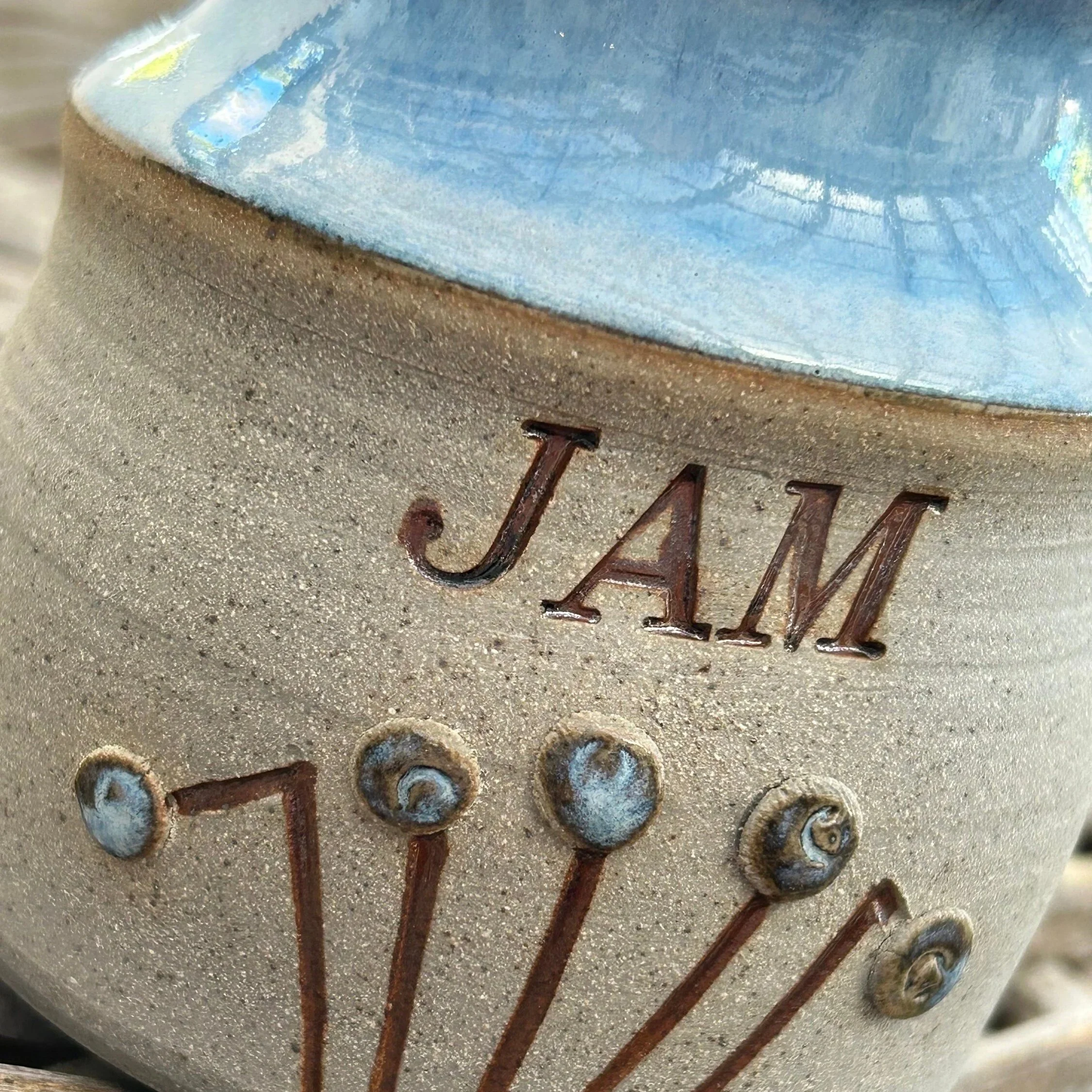 Close-up of hand-carved sunburst motif with raised glaze dots