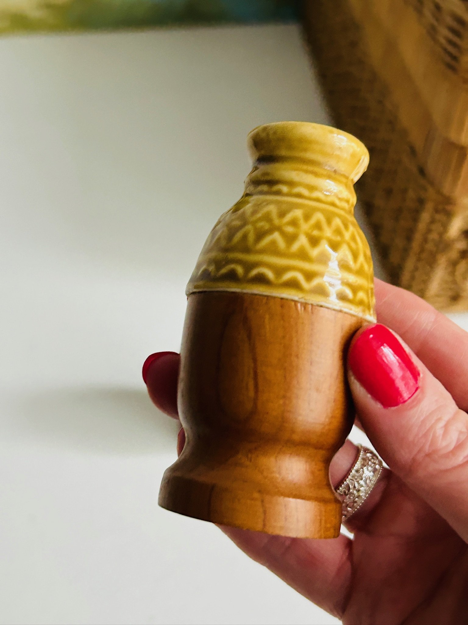 Side view of a single vintage wood and ceramic shaker held in hand, showing the turned shape and glossy glaze
