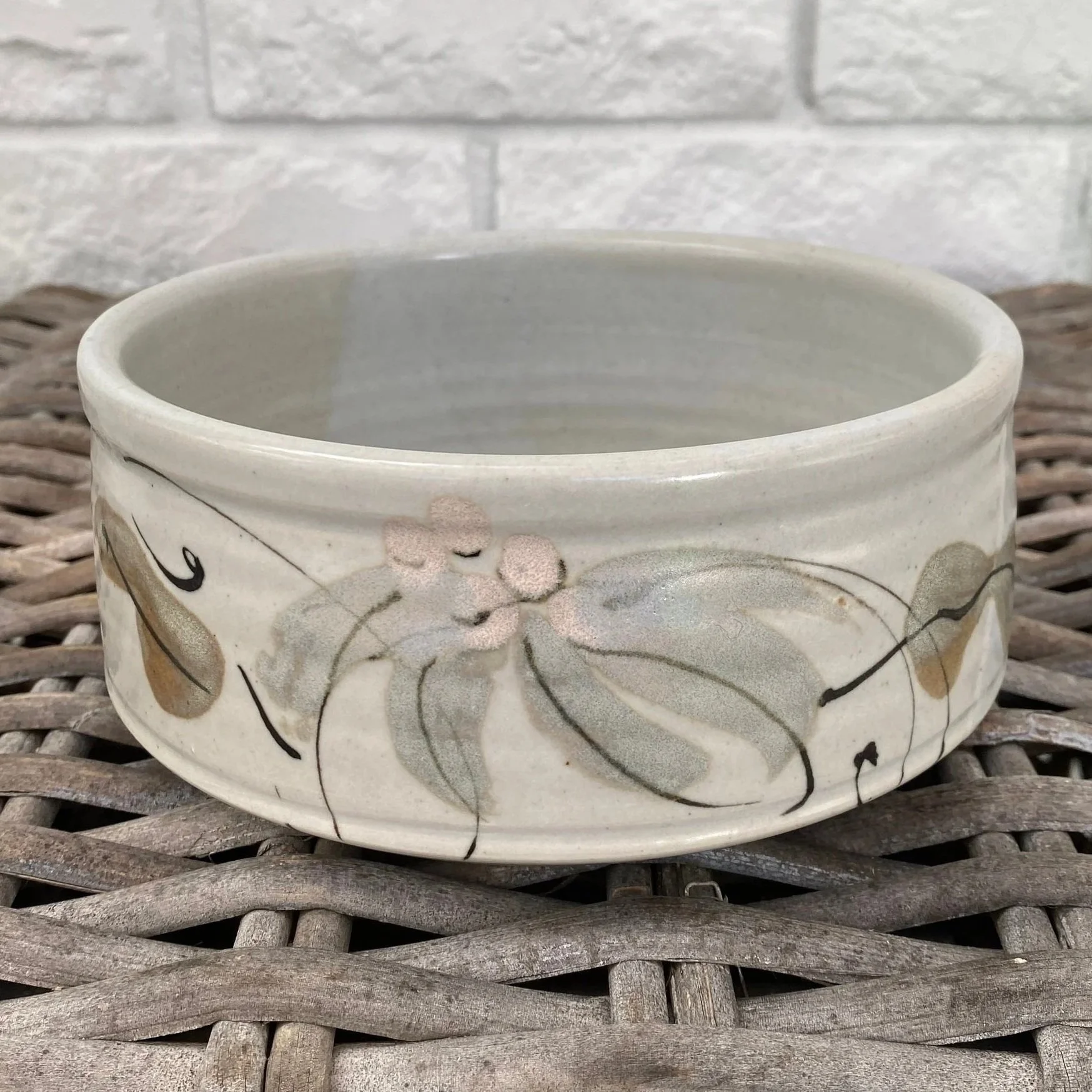 Side view of handmade bowl with painted gum leaf and blossom design