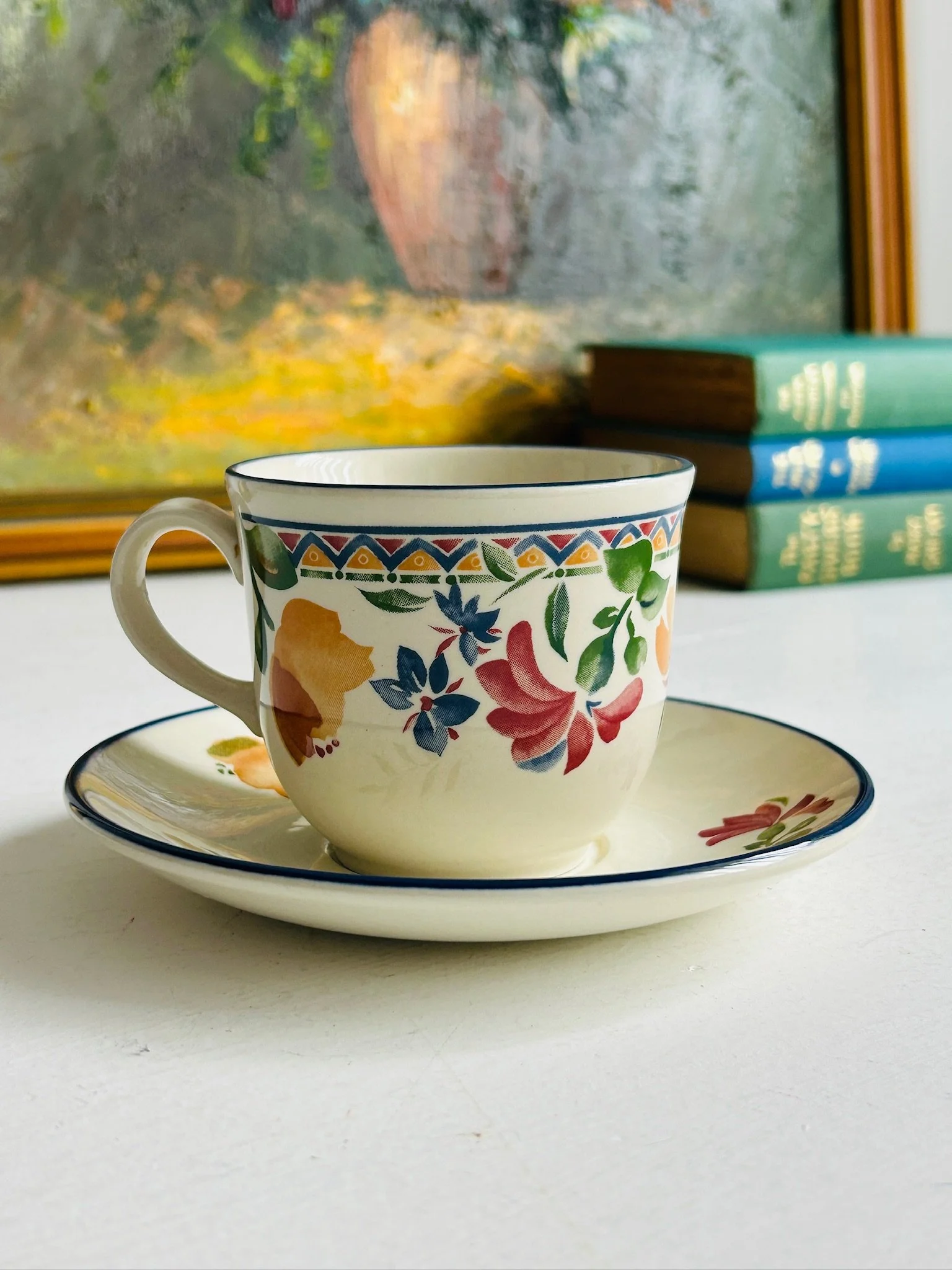 Angled side view of the Staffordshire ‘Calypso’ tea cup and saucer, showing multiple floral motifs in pink, blue, yellow, and green with the patterned border.