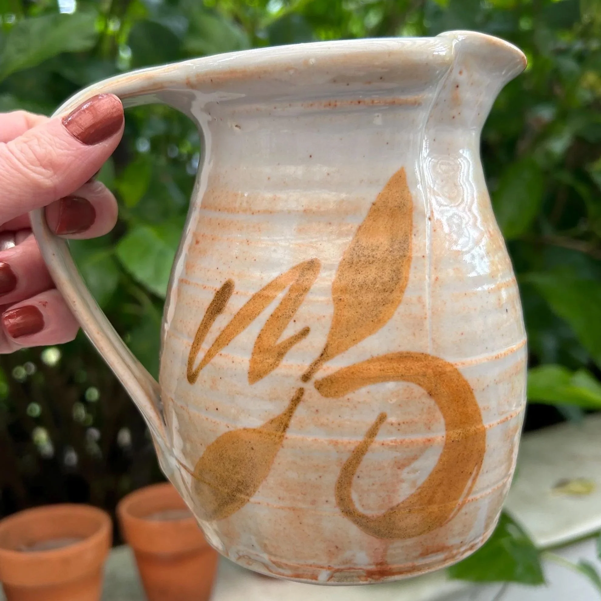 Side view of pottery creamer jug showing brushstroke design and handle
