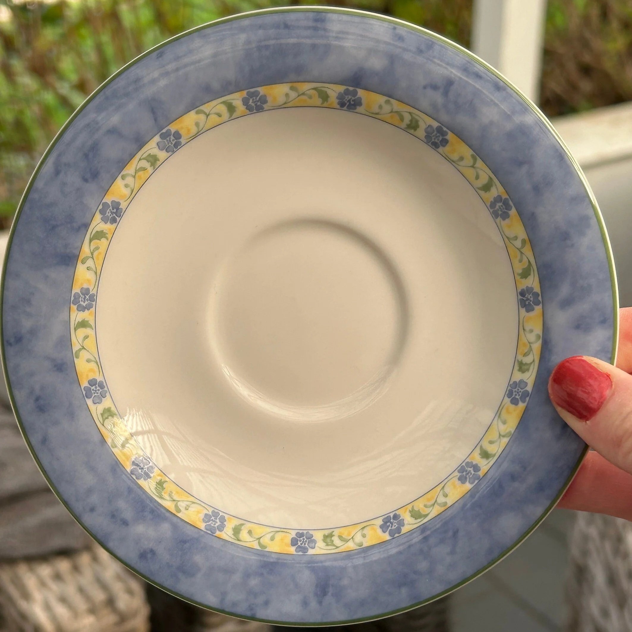 Handheld view of Royal Doulton “Summer Breeze” saucer showing full floral border