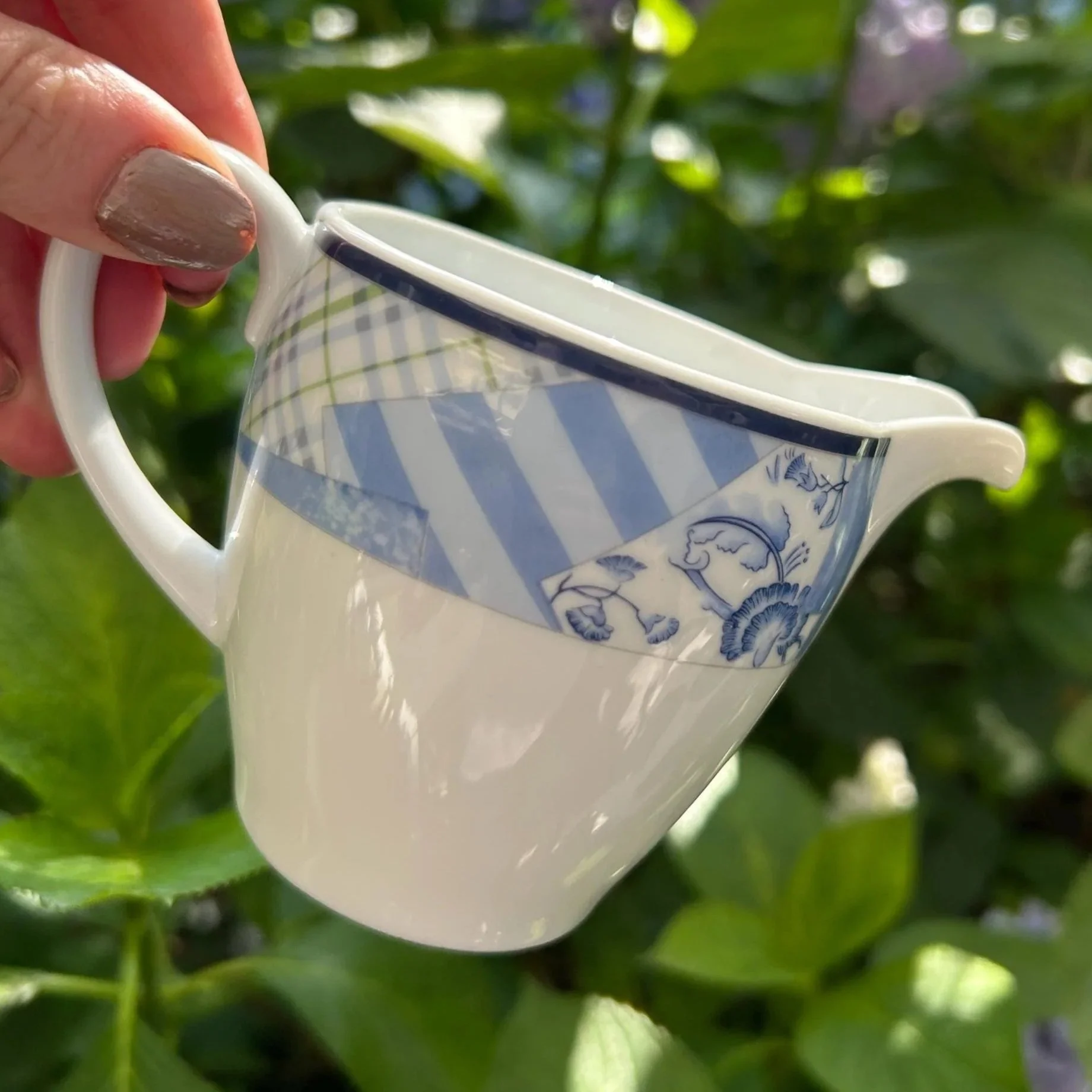 Side view of the creamer showing its spout, handle and blue striped and floral Indigo design