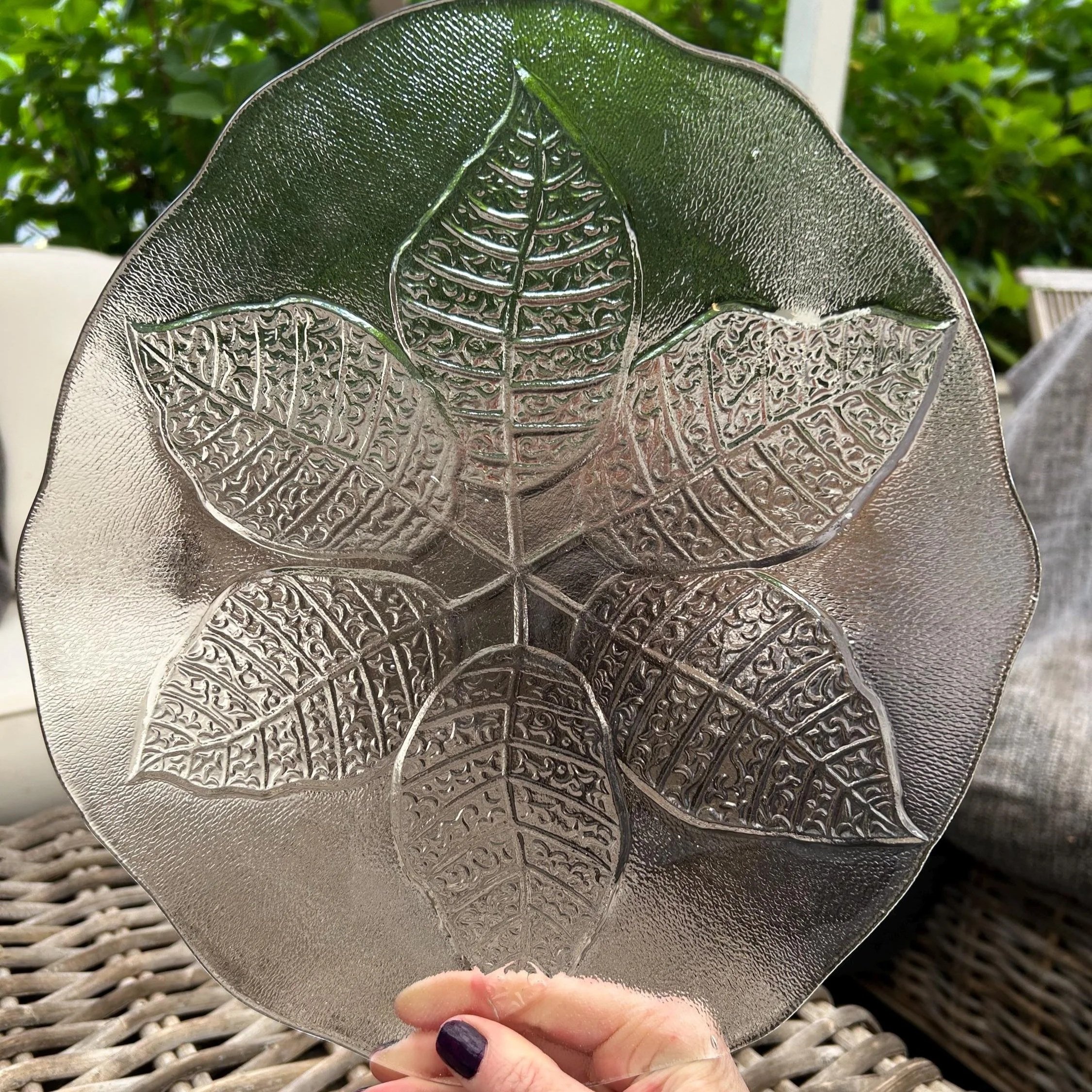 Overhead view of Kosta Boda frosted leaf plate on rattan chair, showing full embossed design
