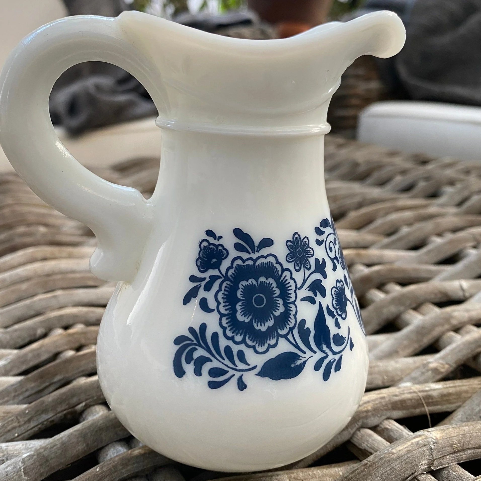 Front view of Avon milk glass pitcher with bold blue floral motif