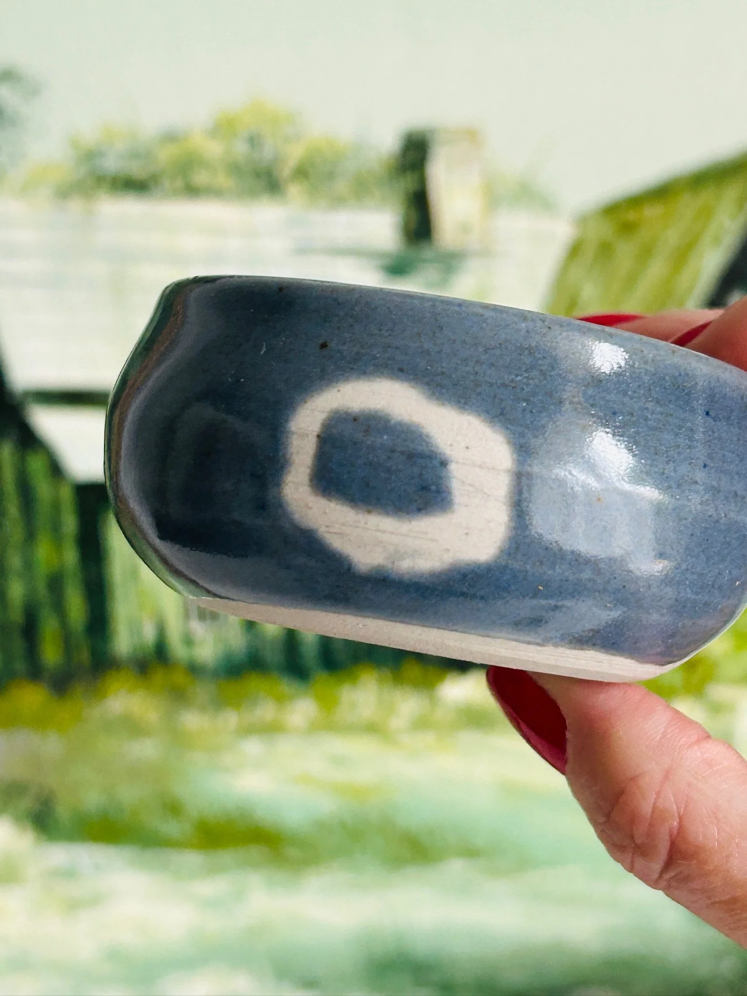 Close side view of the bowl showing the irregular handmade form and white ring motif against the blue-grey glaze
