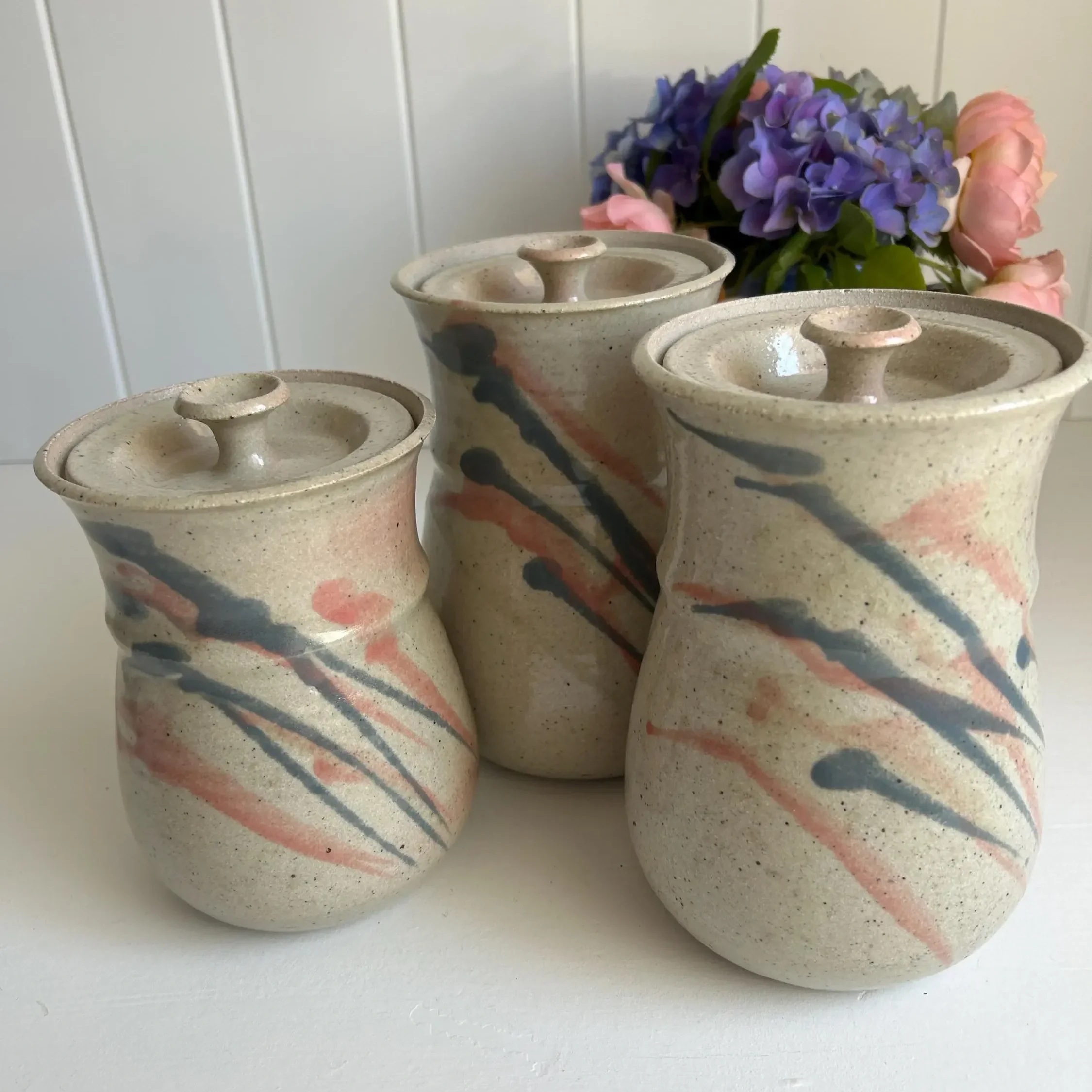 Angled side view of the canisters against a floral backdrop