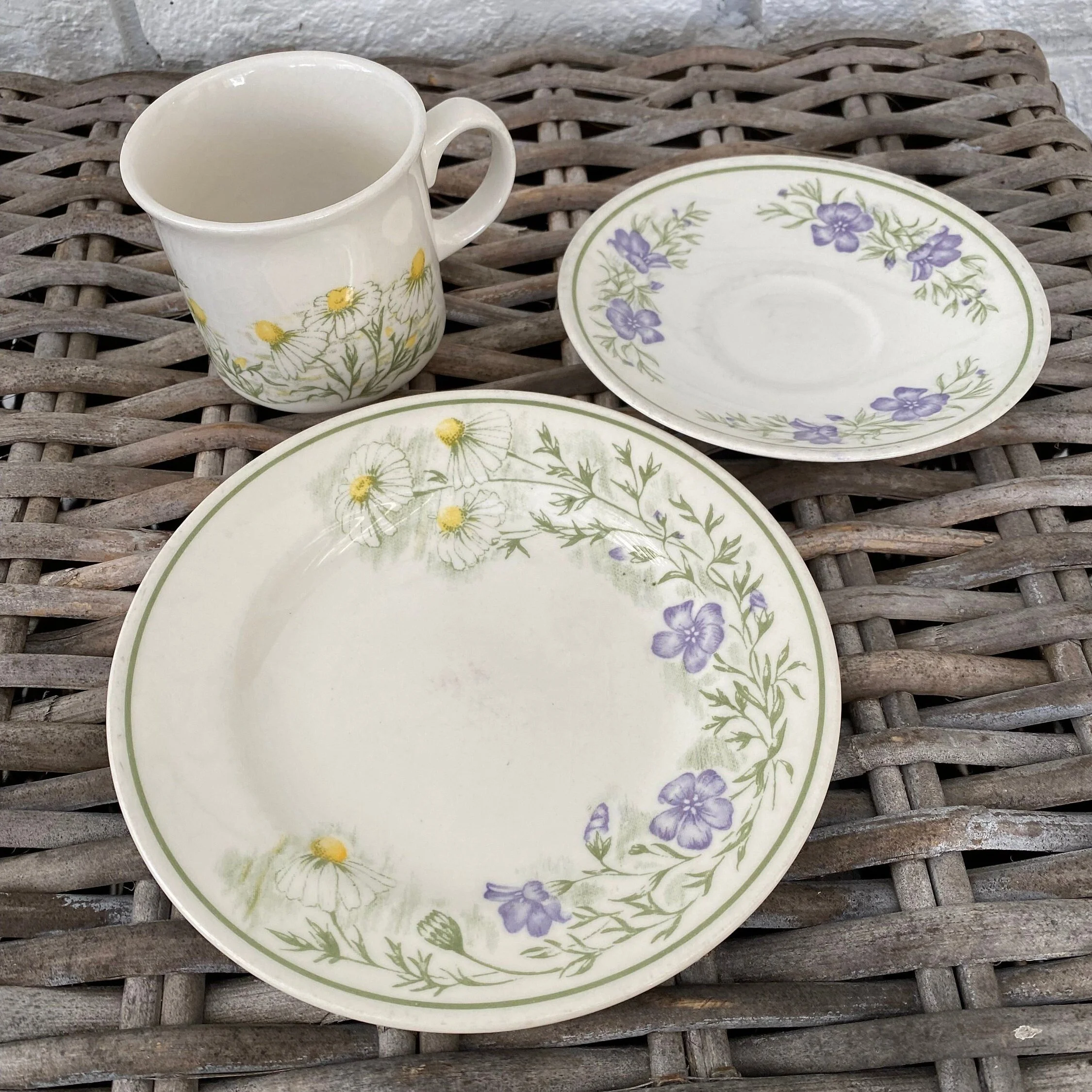 Full view of Churchill tea trio set with floral detailing, arranged on wicker surface