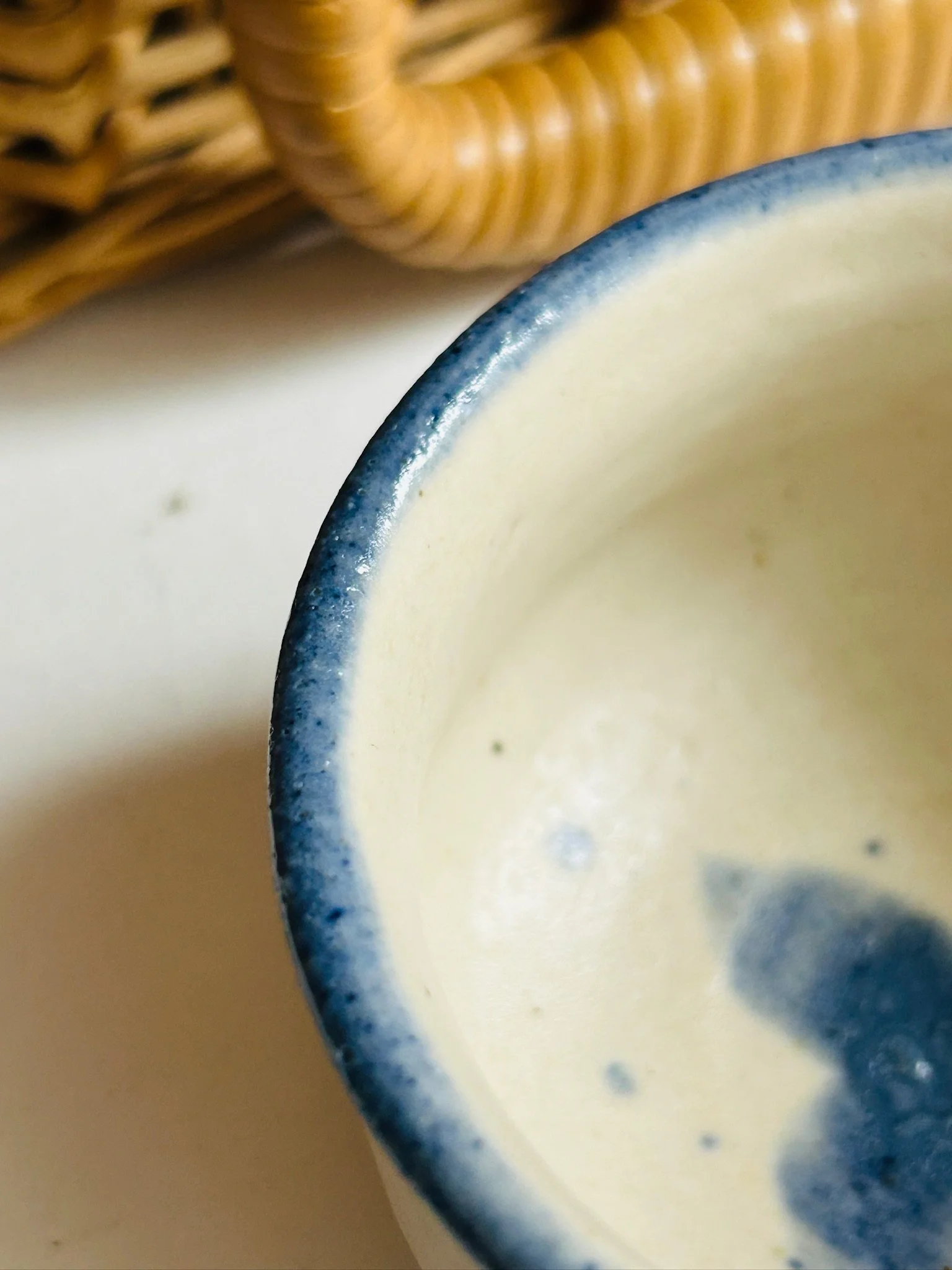 Close-up of the bowl rim and interior glaze with partial view of the blue floral centre design
