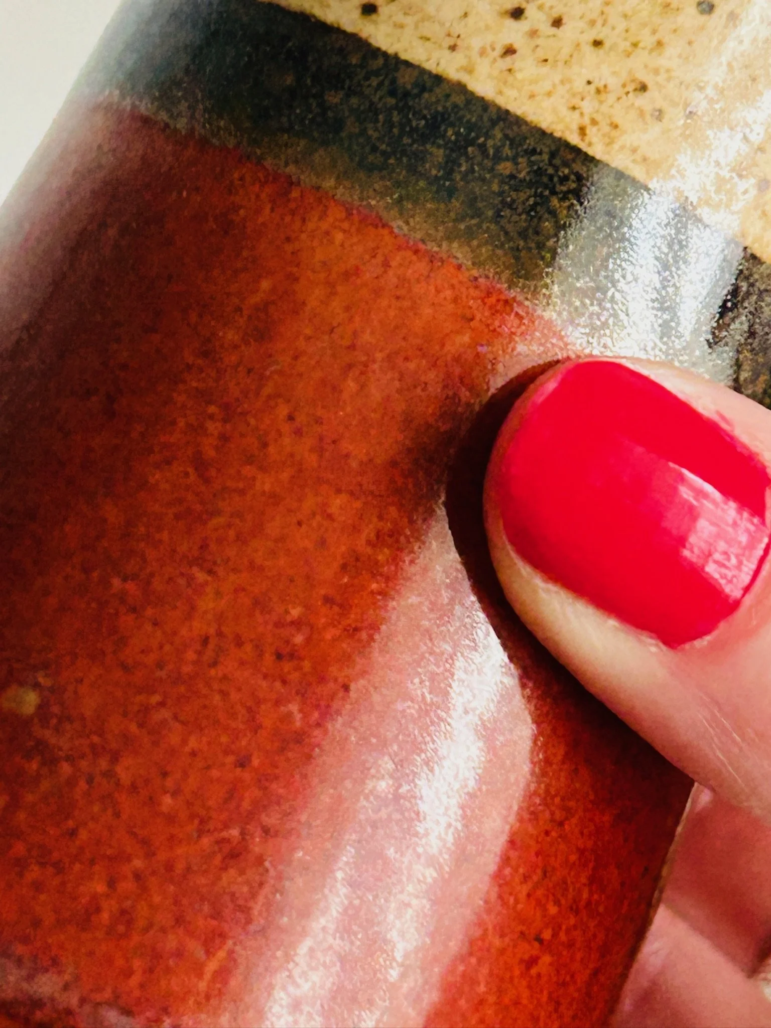 Extreme close-up of one shaker body held in hand, highlighting the rich reddish-brown glaze and glossy finish.