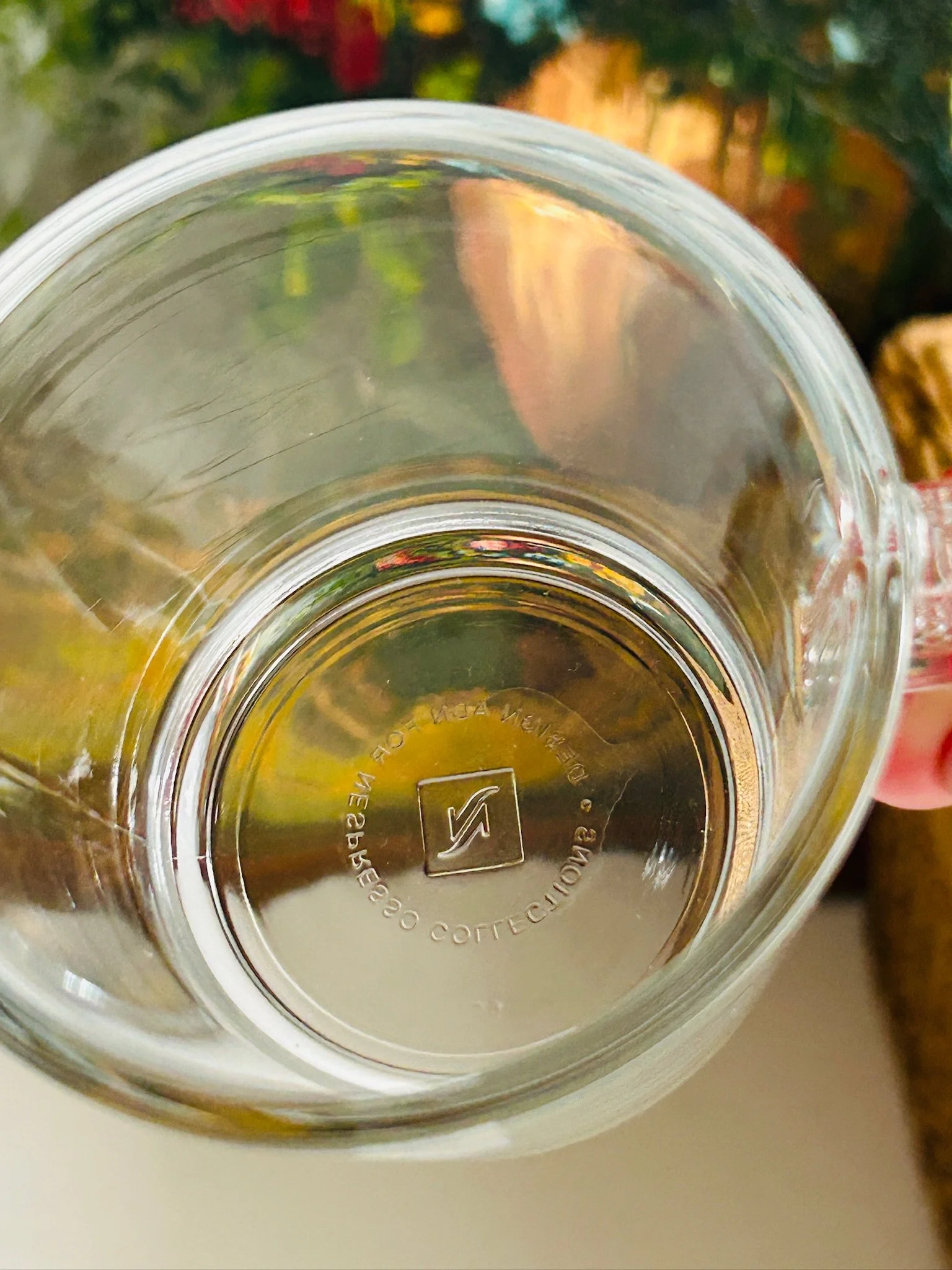 Interior view of the base of a Nespresso glass cup showing the moulded underside mark through the glass