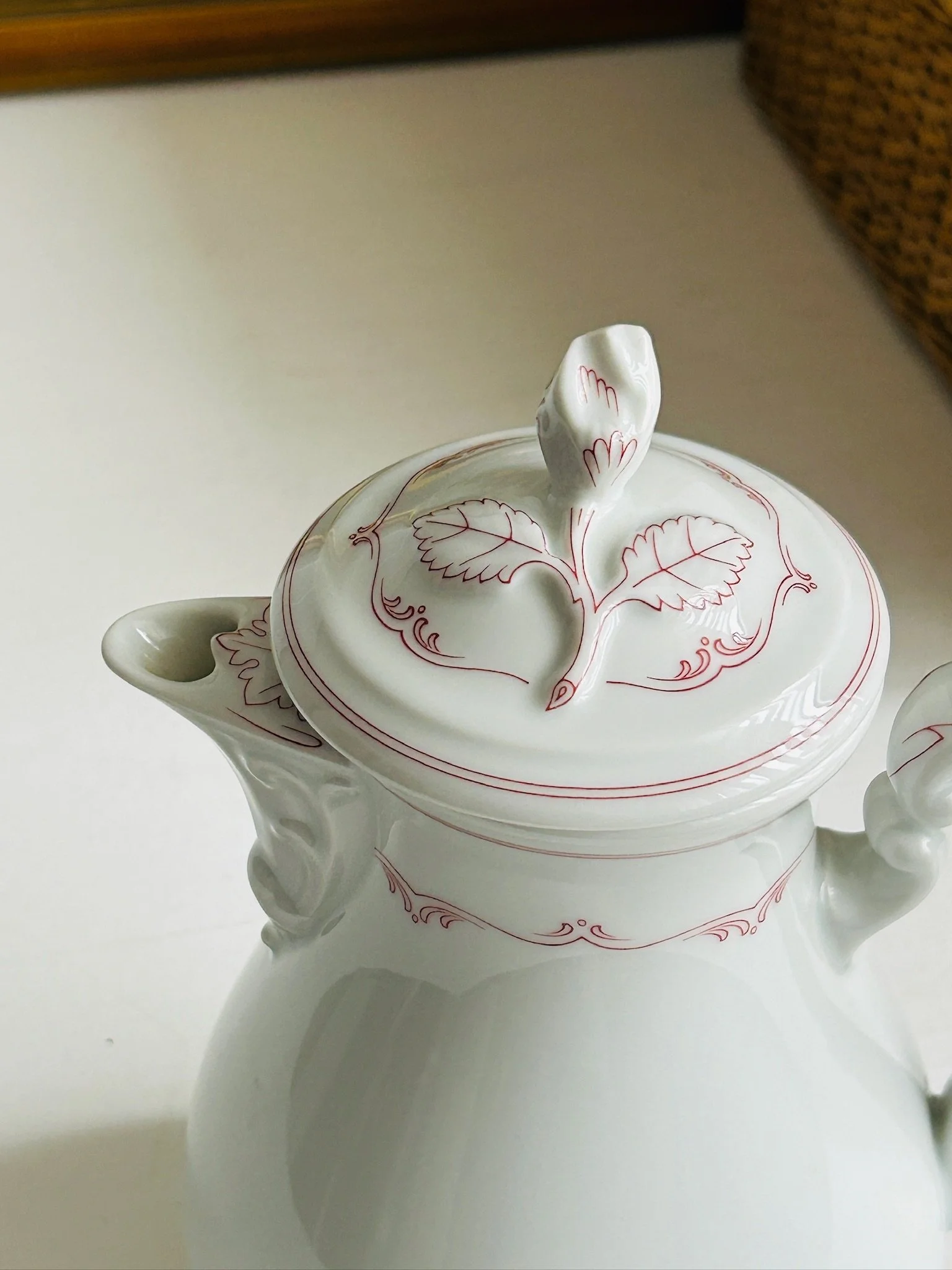 Overhead angled view of the coffee pot showing the domed lid, leaf finial, spout, and curved handle.