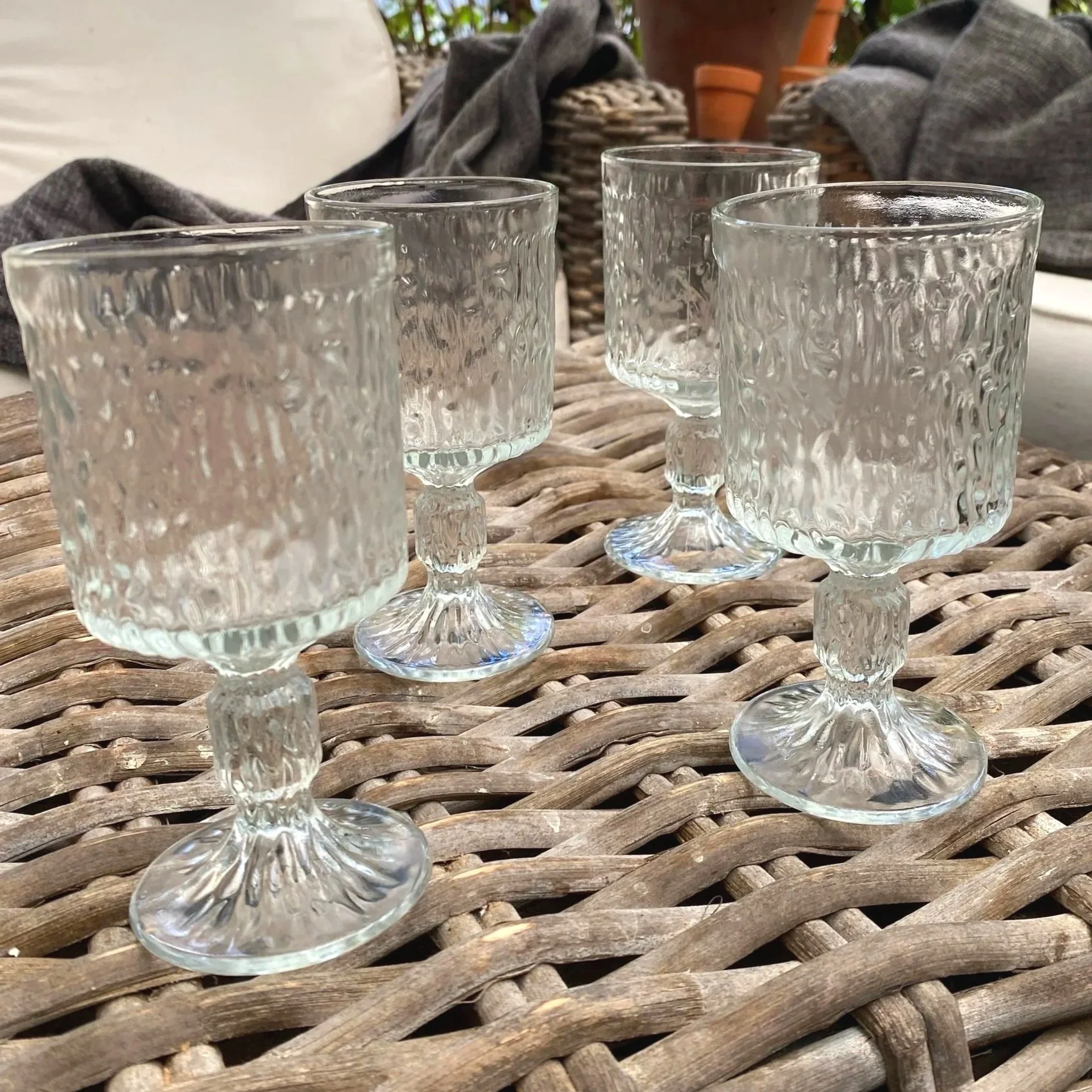 Side angle view of full set of five Ravenhead Siesta wine glasses on wicker table