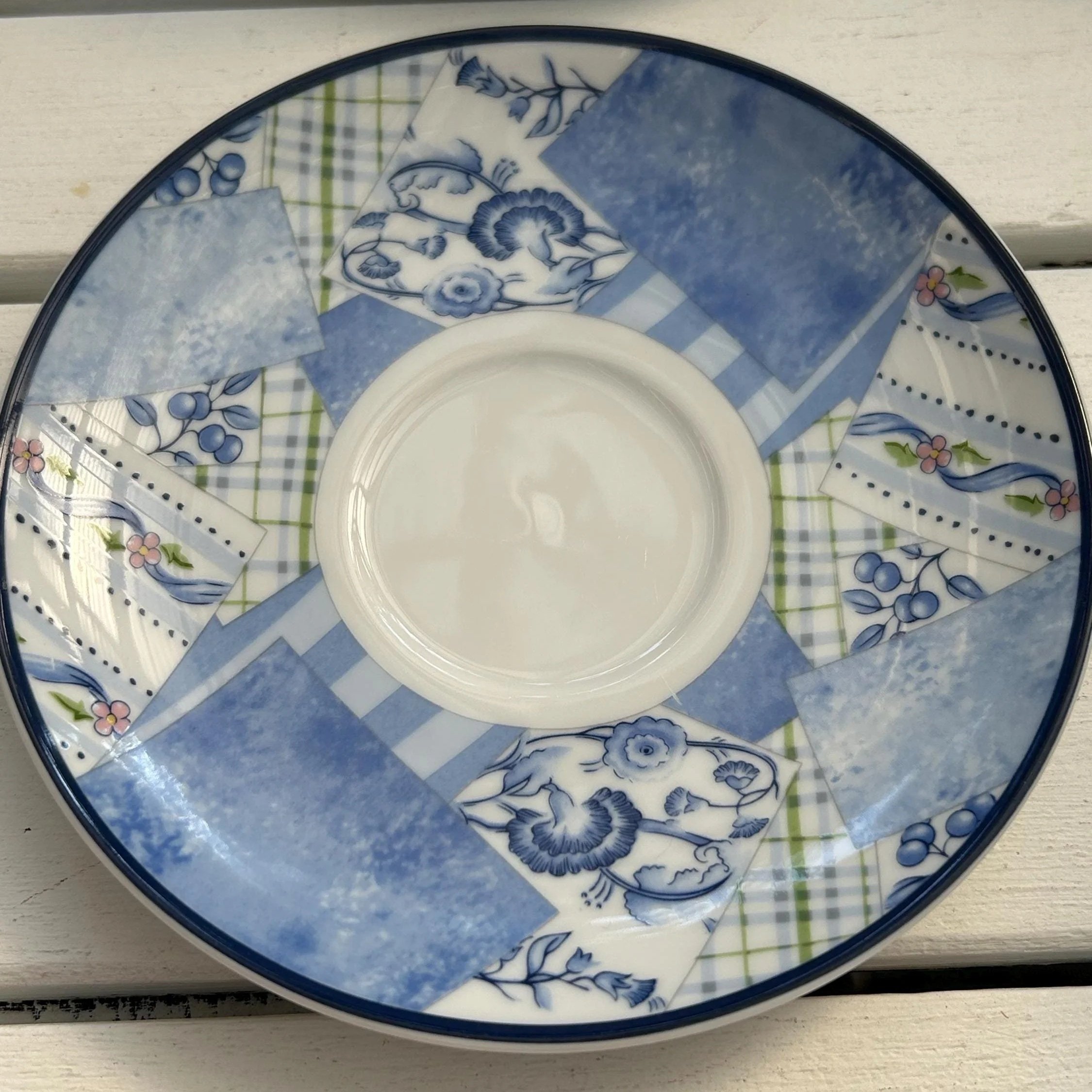 Top view of the saucer showing the blue patchwork pattern with floral, stripe, and check details
