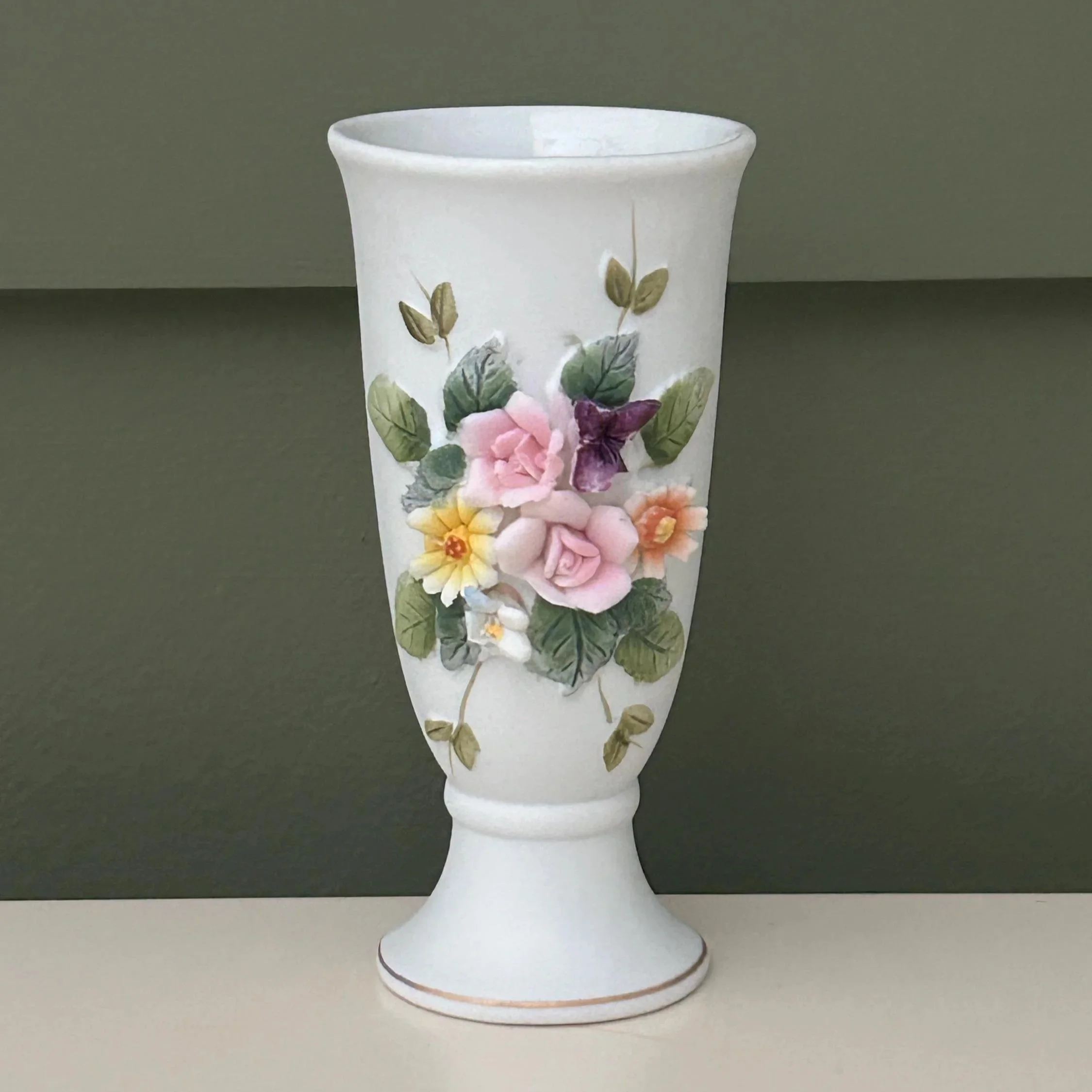 Tall pitcher vase with detailed raised floral design and gold trim