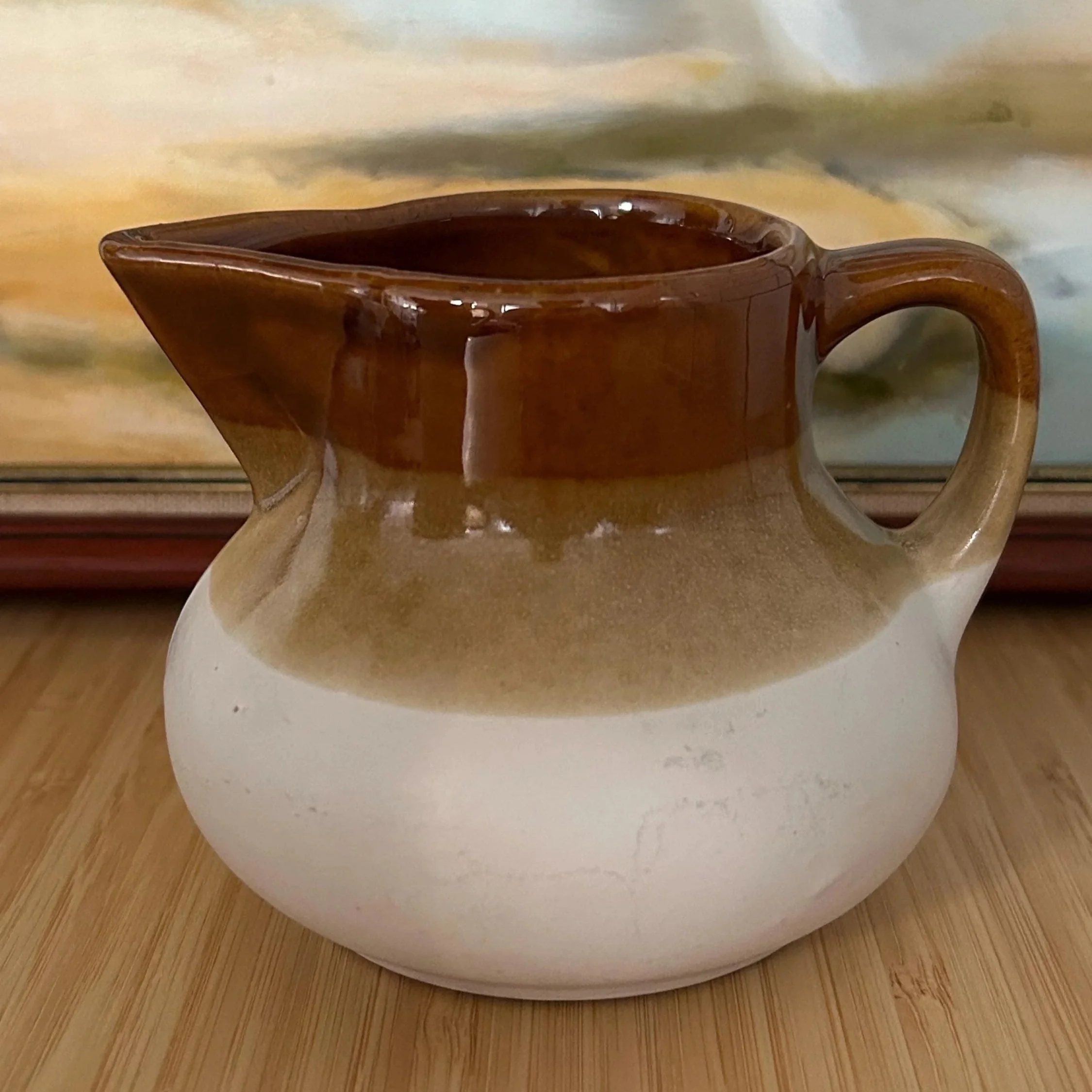 Creamer with rich brown glaze and soft round shape on timber surface